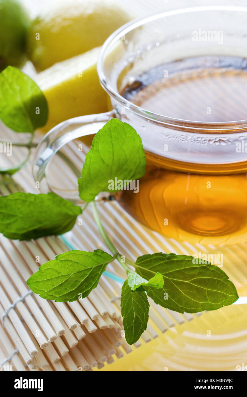 Il tè in tazza di vetro con limone e foglie di menta fresca a base di erbe - tè di guarigione come rimedio casalingo Foto Stock