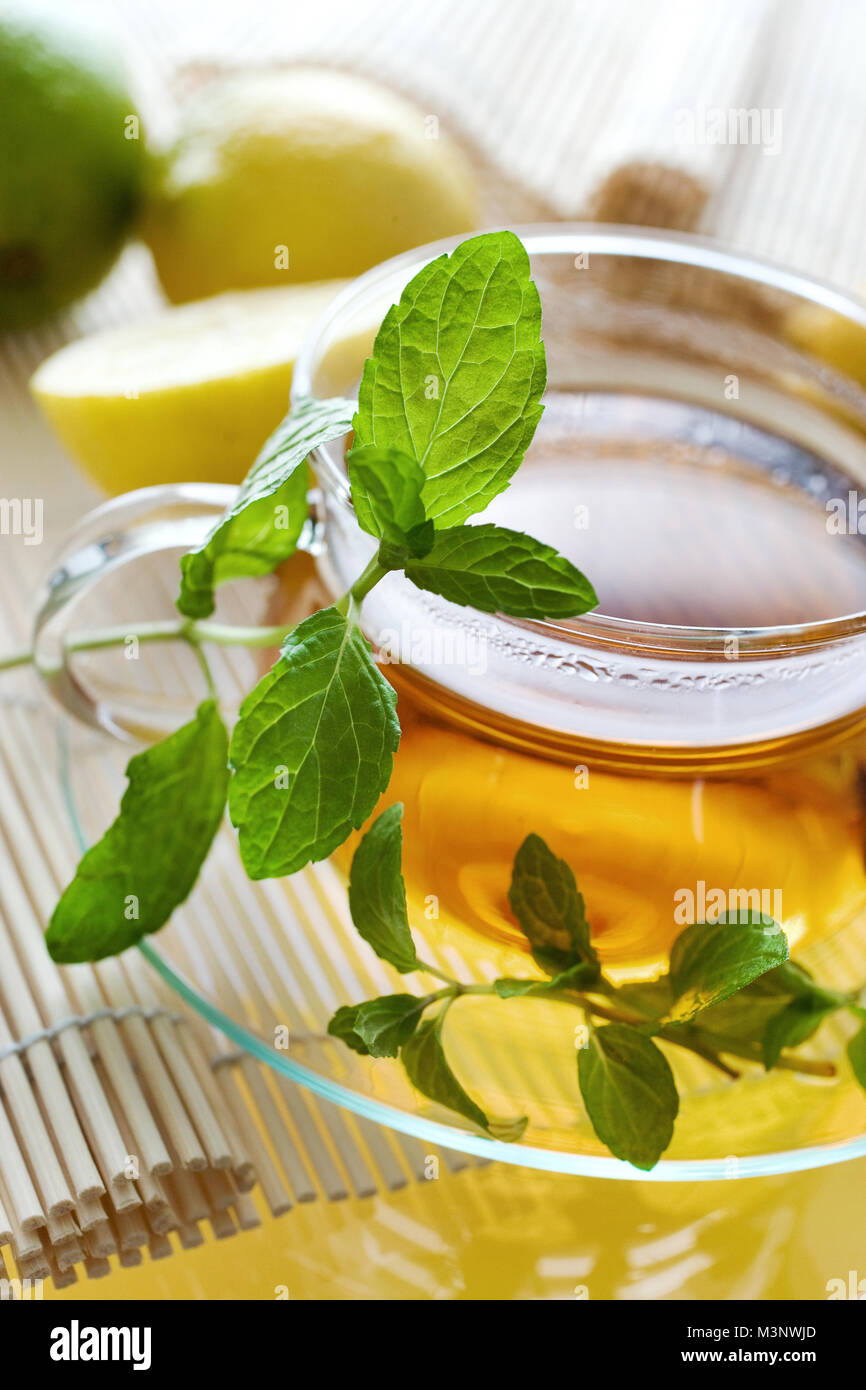 Il tè in tazza di vetro con limone e foglie di menta fresca a base di erbe - tè di guarigione come rimedio casalingo Foto Stock