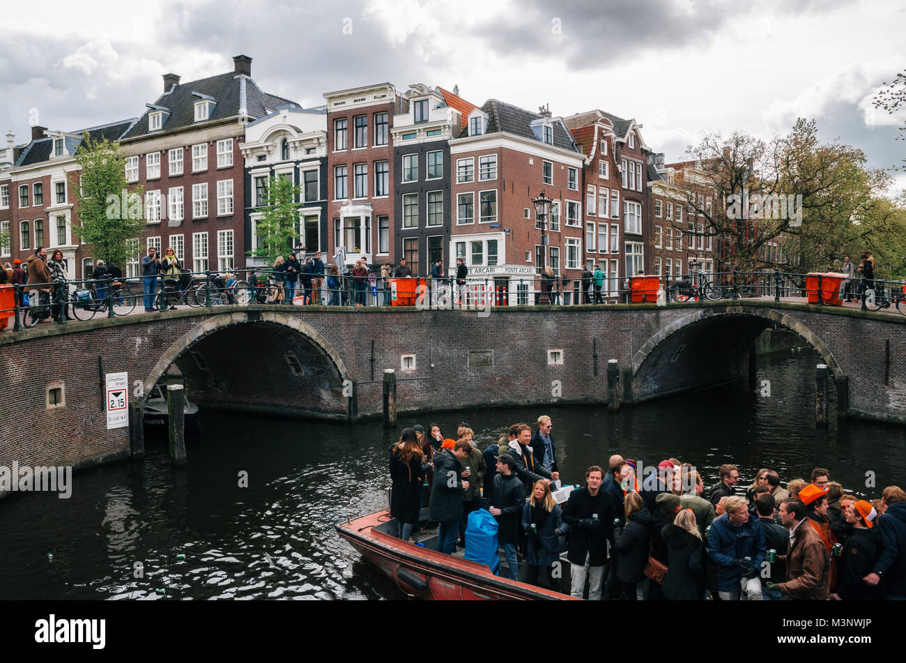 Amsterdam, Paesi Bassi - 25 April, 2017: la popolazione locale e i turisti di marcia su barche sotto stretti ponti e partecipare a celebrare il re del giorno lungo Foto Stock