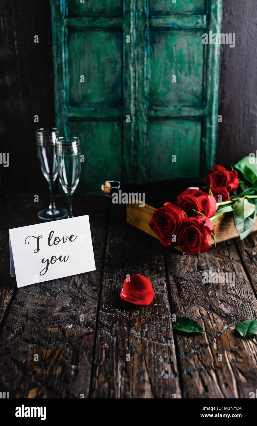 Ti amo bigliettino, rose rosse e bottiglia di champagne con gli occhiali nel vassoio Foto Stock