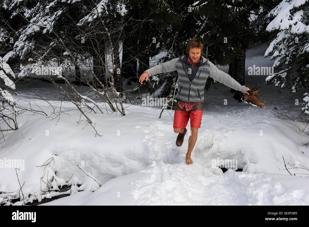 Un uomo cammina attraverso la neve a piedi nudi durante una escursione al Lago Trillium nel Mt. Hood National Forest in Oregon. Foto Stock