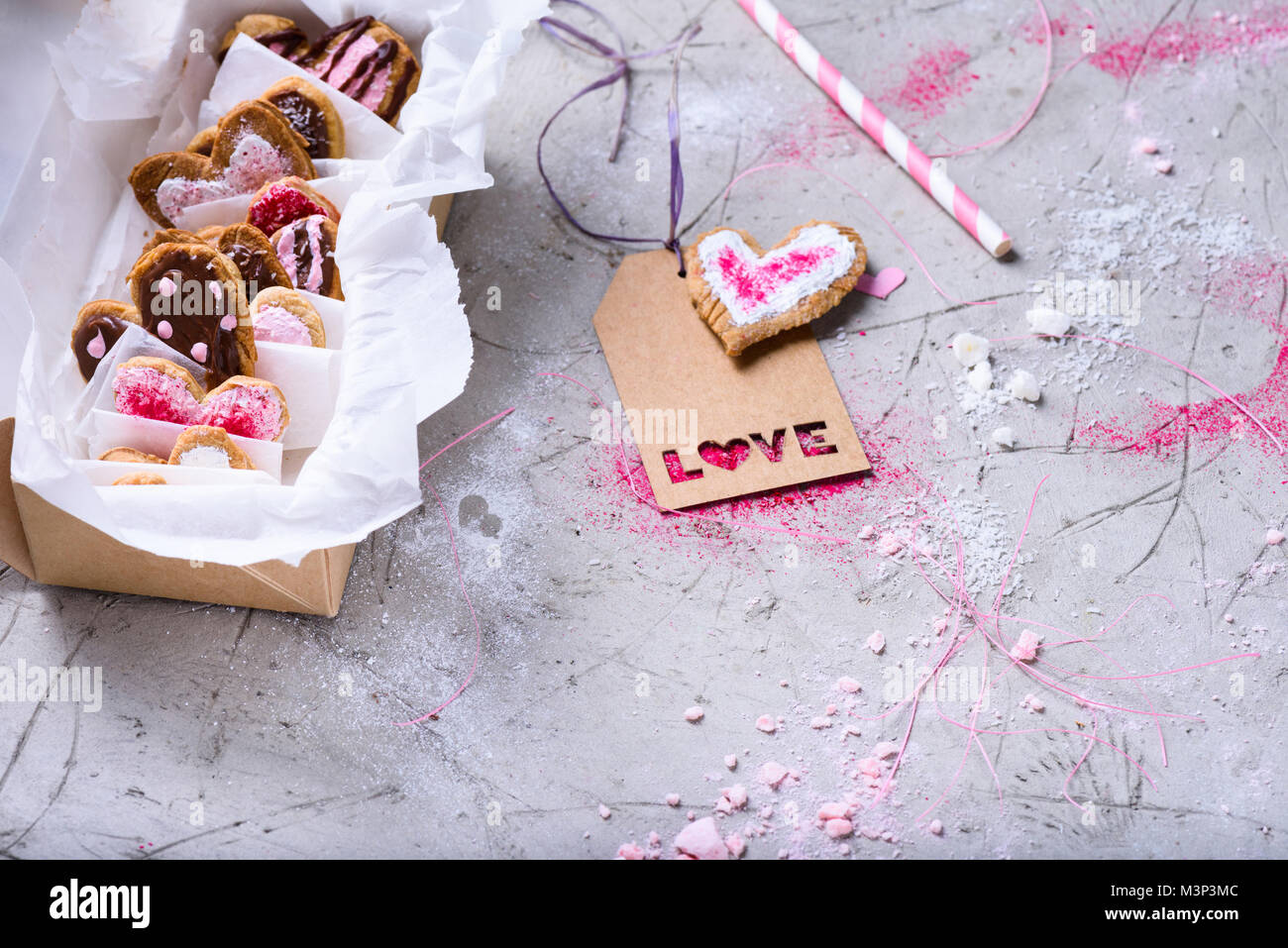 Vista ravvicinata di scatola con dolci biscotti di San Valentino con amore tag sulla superficie grigia Foto Stock