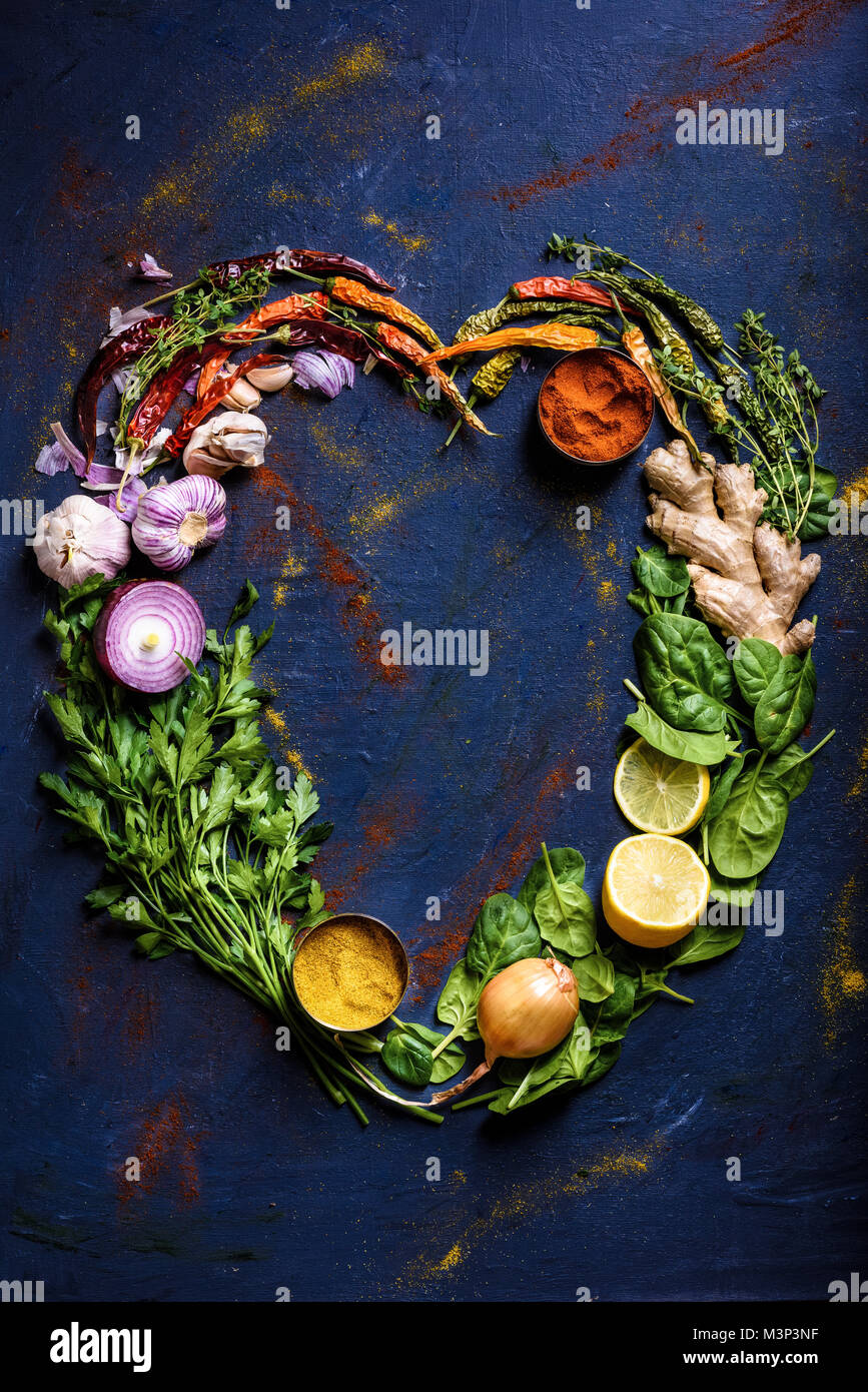 Vista superiore del cuore realizzato da erbe, spezie e verdure su blu Foto Stock