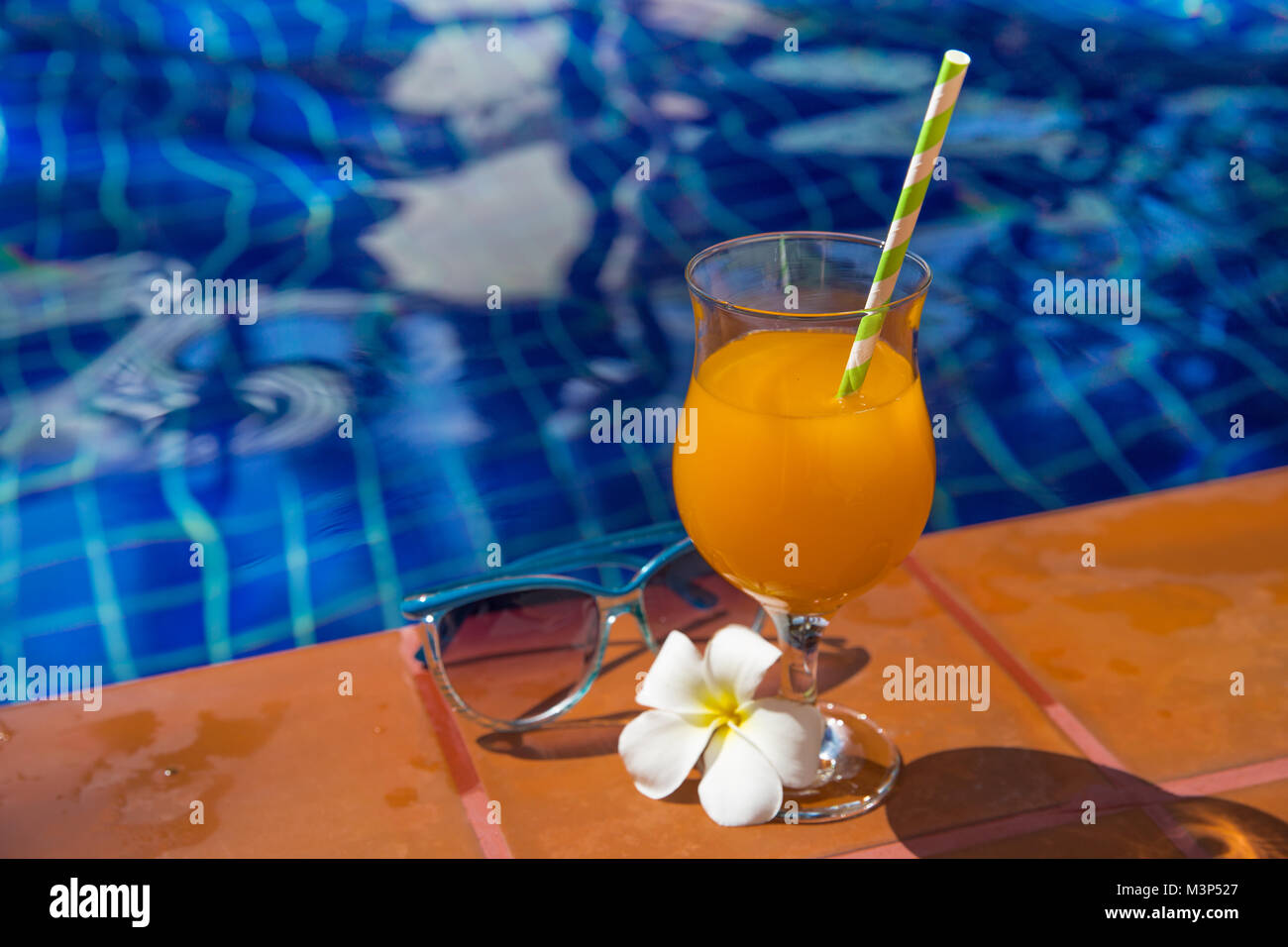 Succo di arancia con gli occhiali da sole sul al bordo della piscina - vacanza concetto tropicale Foto Stock