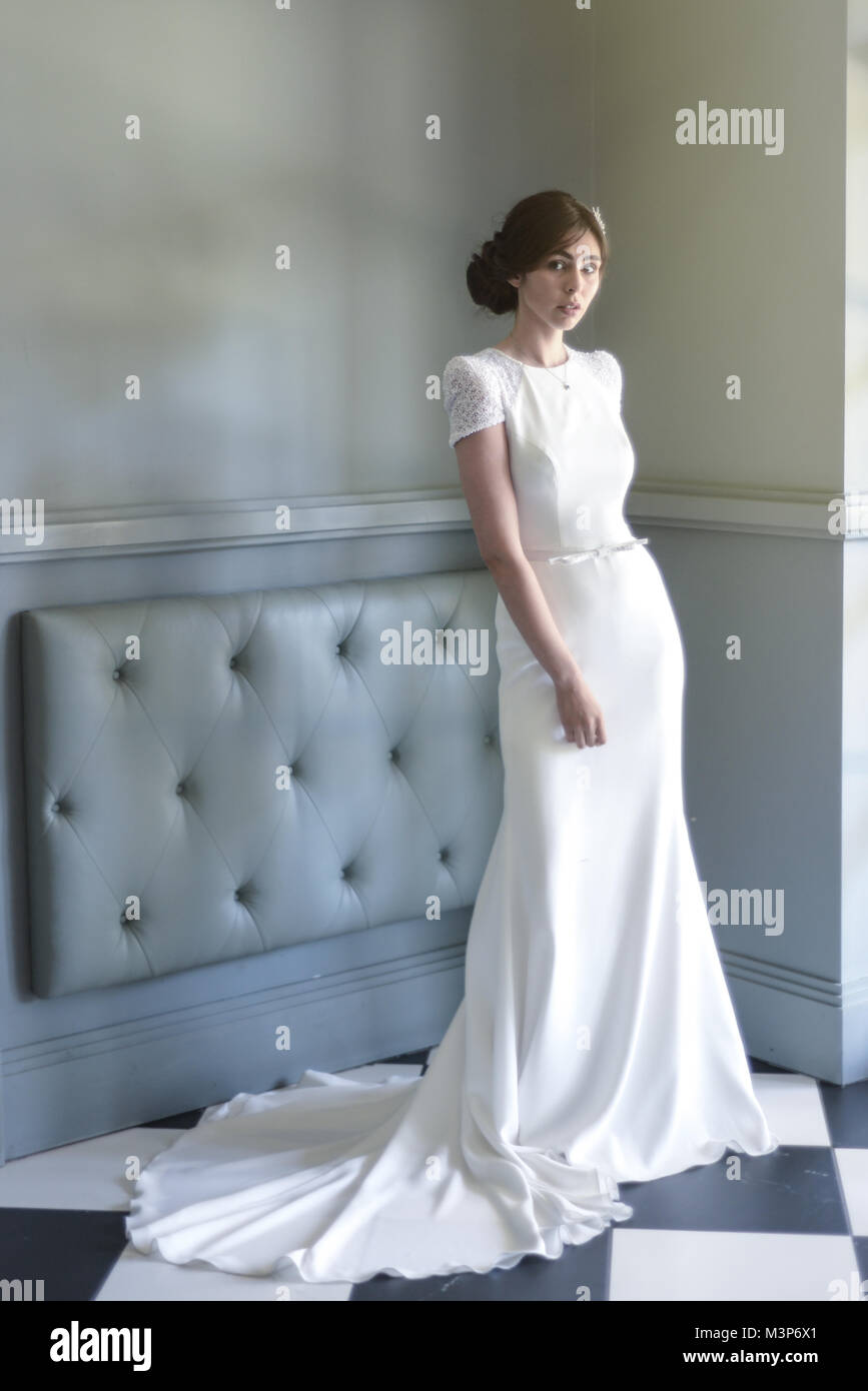 Una bella dai capelli scuri sposa che indossa una dotata di un costoso abito da sposa in una giornata di sole- luminosamente illuminata Foto Stock