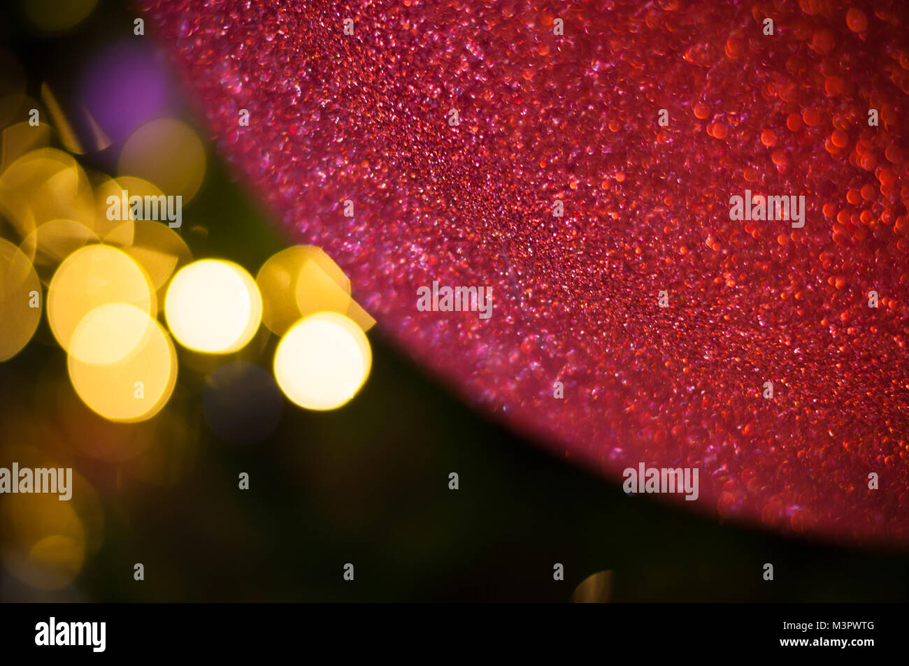 Close up big red glitter palla di Natale con il filo della luce della lampadina bokeh di fondo Foto Stock