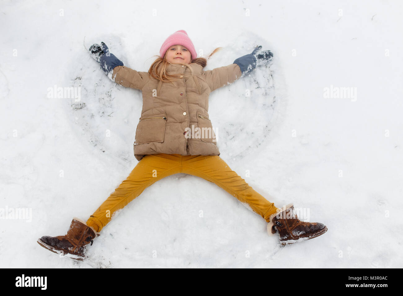 Immagine della ragazza sdraiata sulla schiena nella neve a park Foto Stock