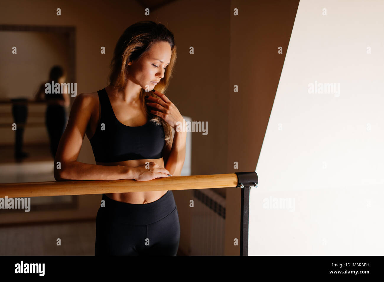 Donna ballerina in posa vicino a barre nel balletto studio Foto Stock