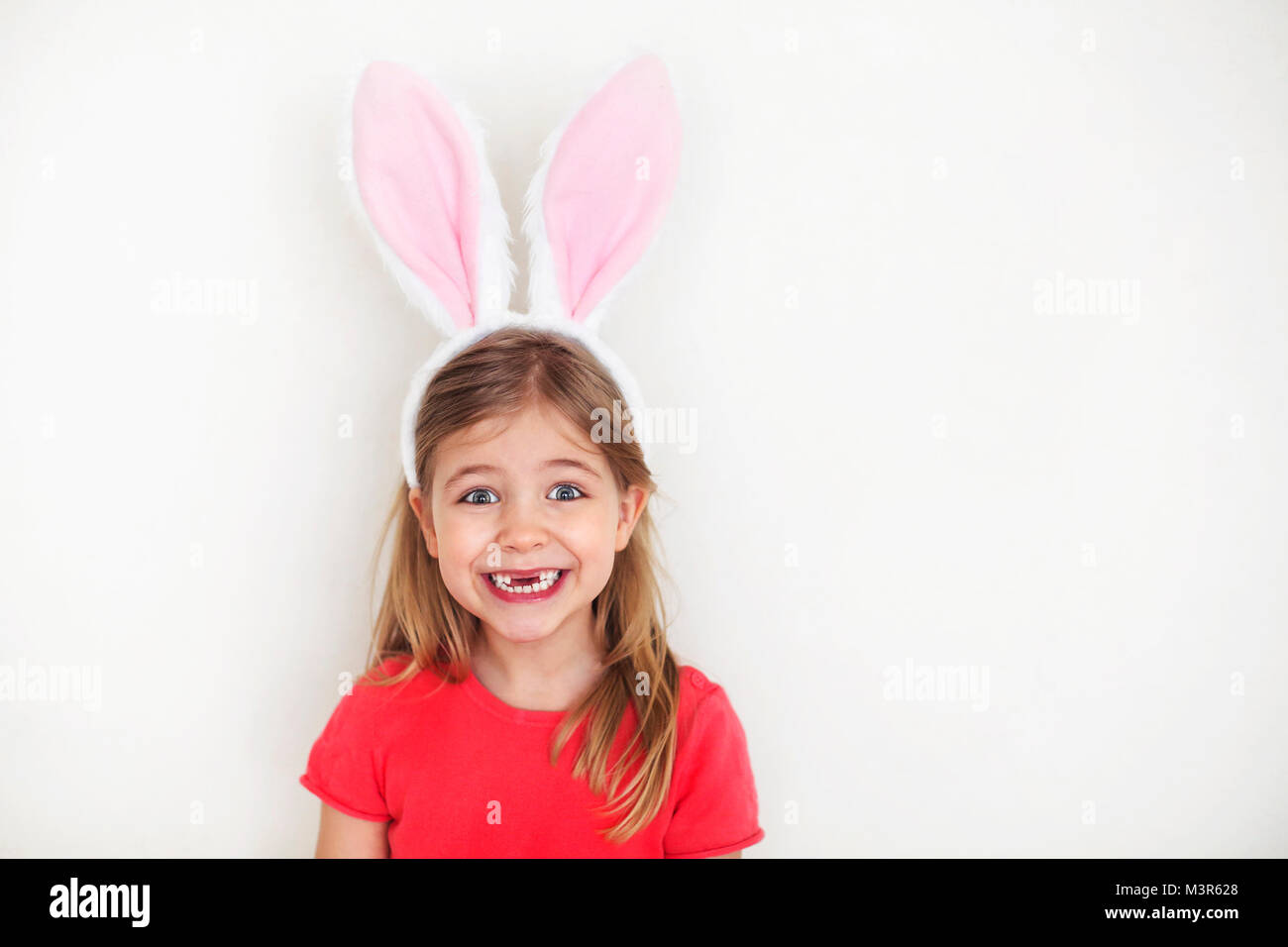 Felice dente perduto bambina indossa divertenti orecchie di coniglietto Foto Stock