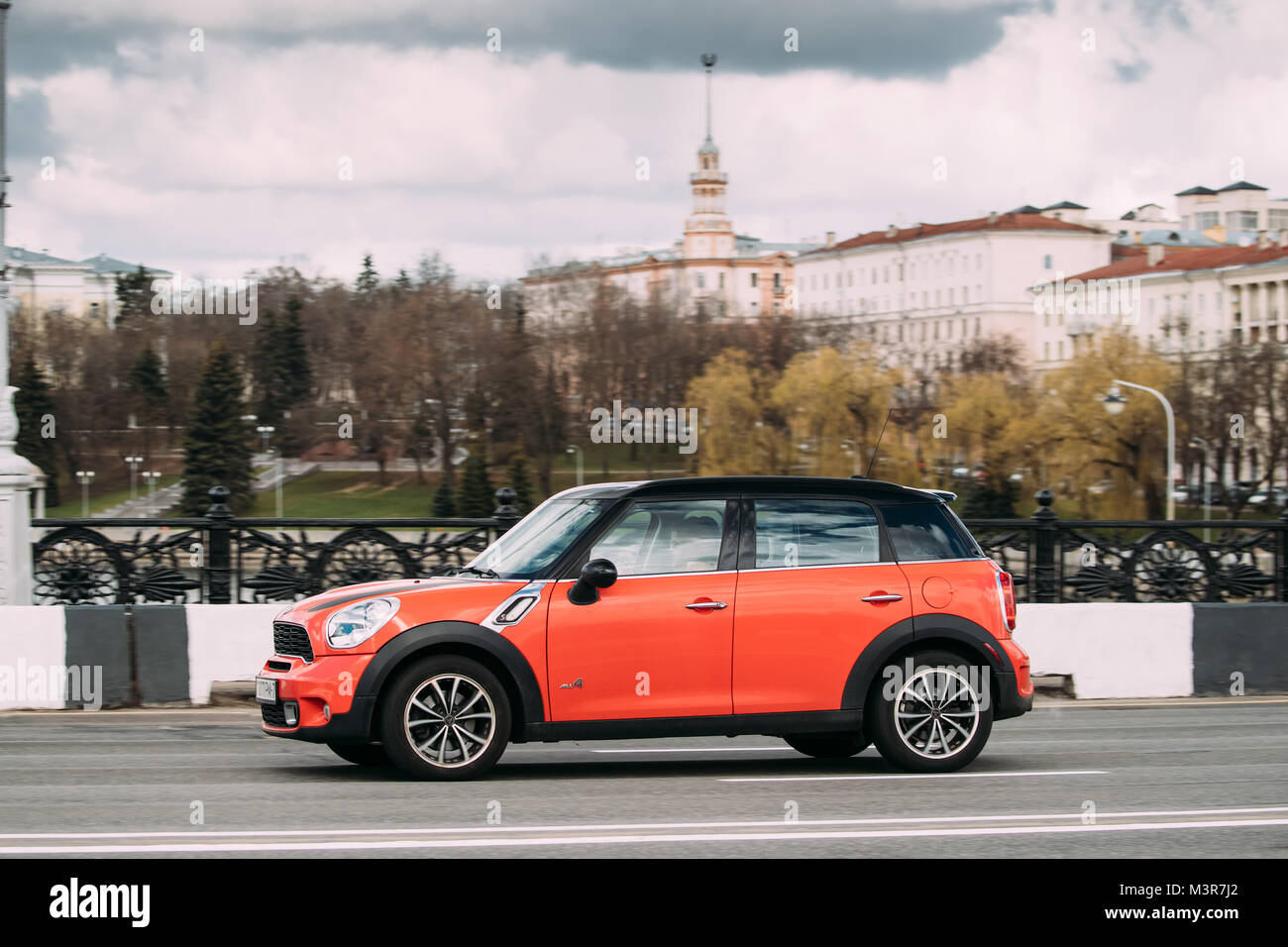 Minsk, Bielorussia - Aprile 7, 2017: Colore Arancione Mini Cooper tutte e 4 le auto con conducente donna in movimento veloce su strada. Foto Stock