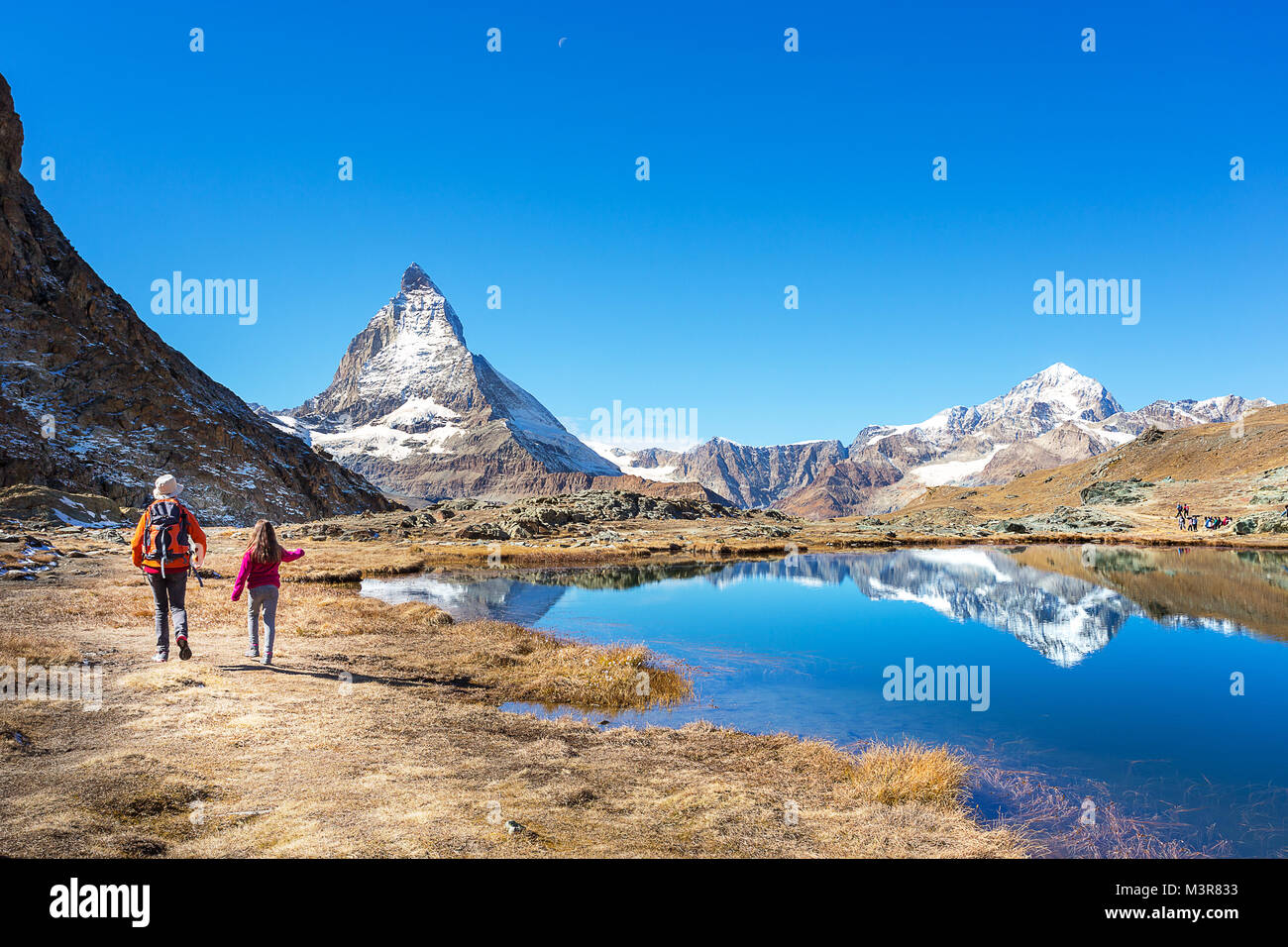 Madre e figlia nello zaino sulla loro vacanza al Monte Cervino con la riflessione sul lago, Zermatt, Svizzera Foto Stock