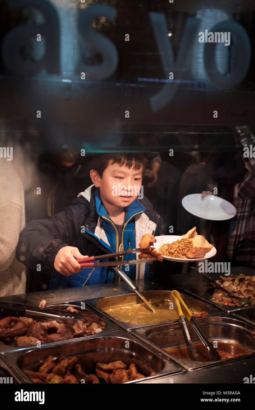 Ragazzo aiutare se stesso sul buffet cinese,China Town , Londra, Regno Unito Foto Stock