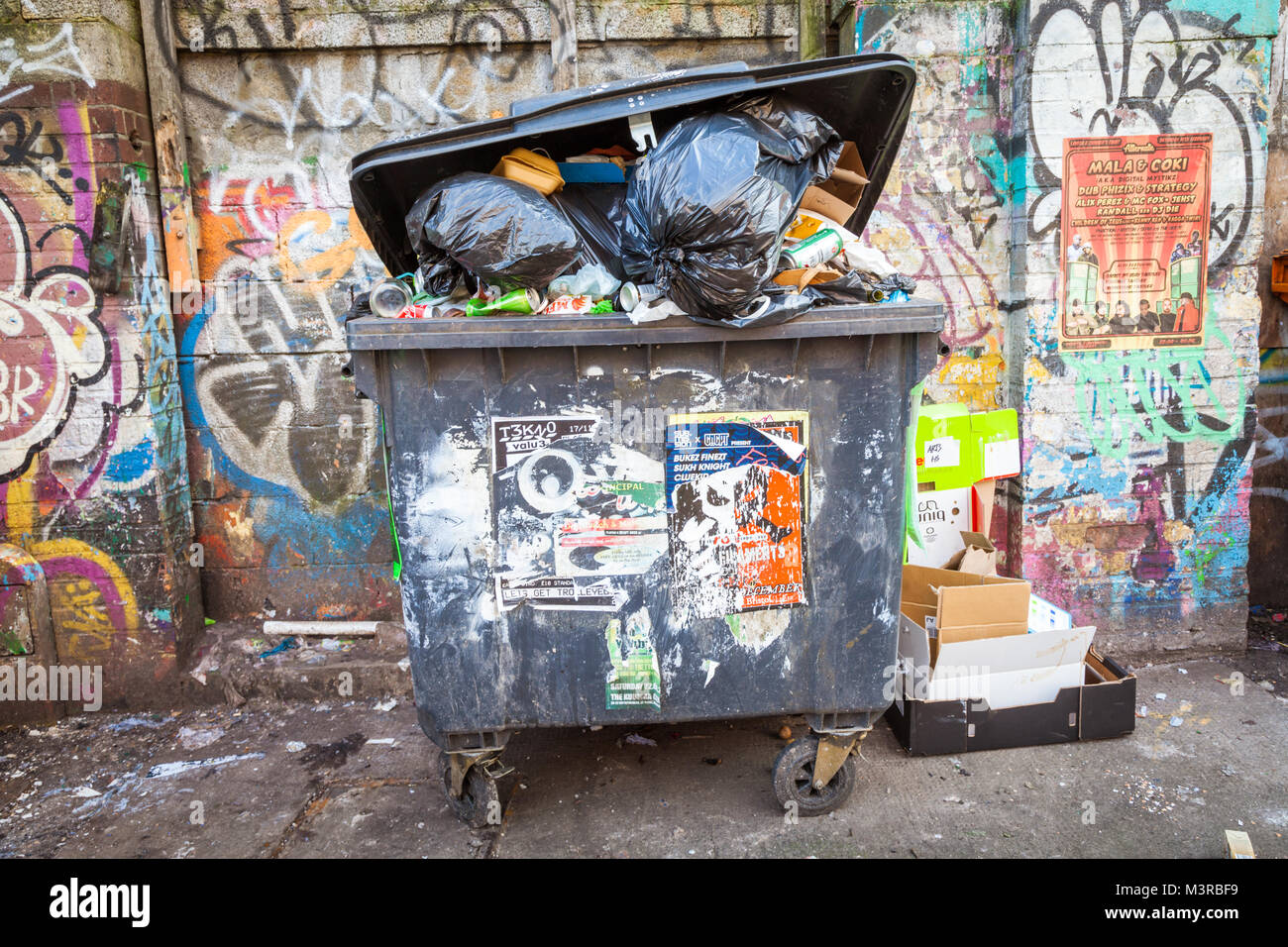 Commercio watse scomparti pieno di spazzatura spazzatura in strada, con grafitti regno unito Foto Stock