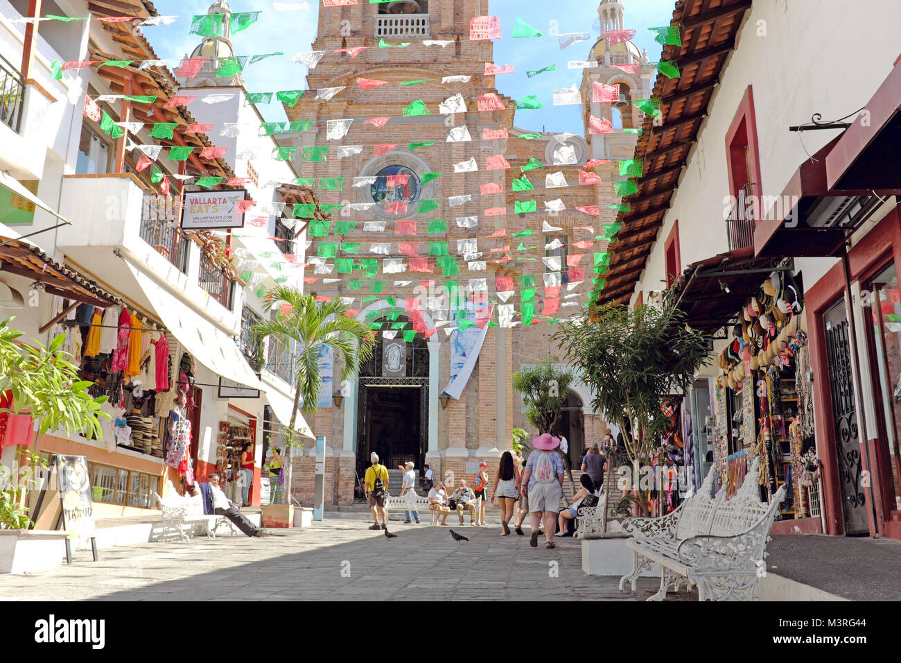 Papel picado bandiere volare al di sopra della strada pedonale che conduce alla mitica Chiesa di Nostra Signora di Guadalupe a Puerto Vallarta, Messico. Foto Stock