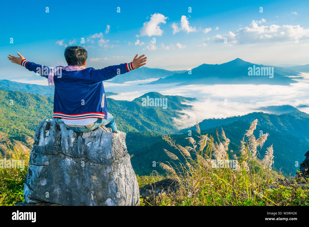 Tanga maschio Traveler sedersi sulla pietra con un bellissimo paesaggio di montagna sfondo, avventura, viaggi, concetto turistico Foto Stock