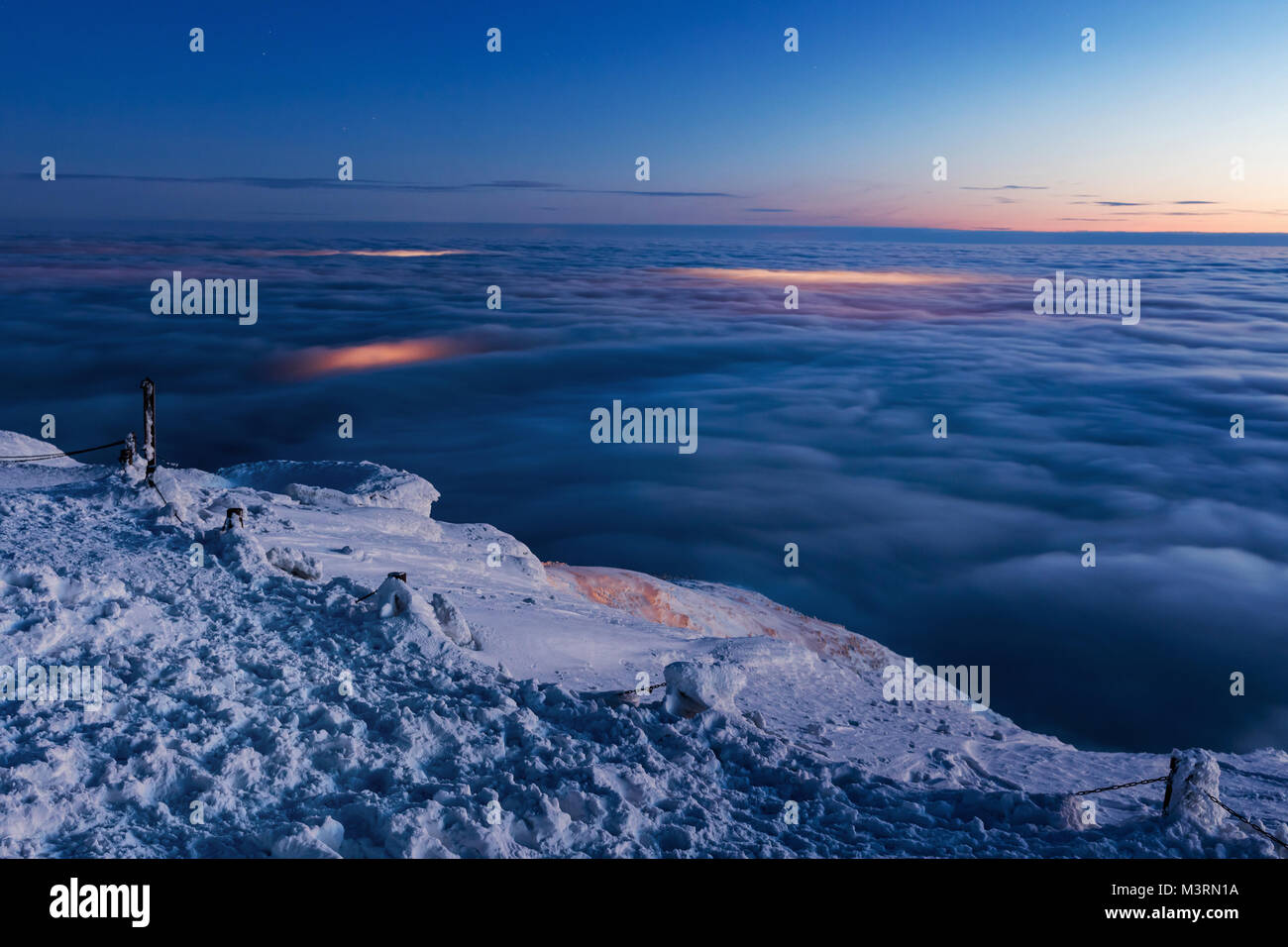 Vista della valle dal vertice del Snezka. Nuvole invertita nella valle, splendente città sotto le nuvole. Krkonocse. Foto Stock