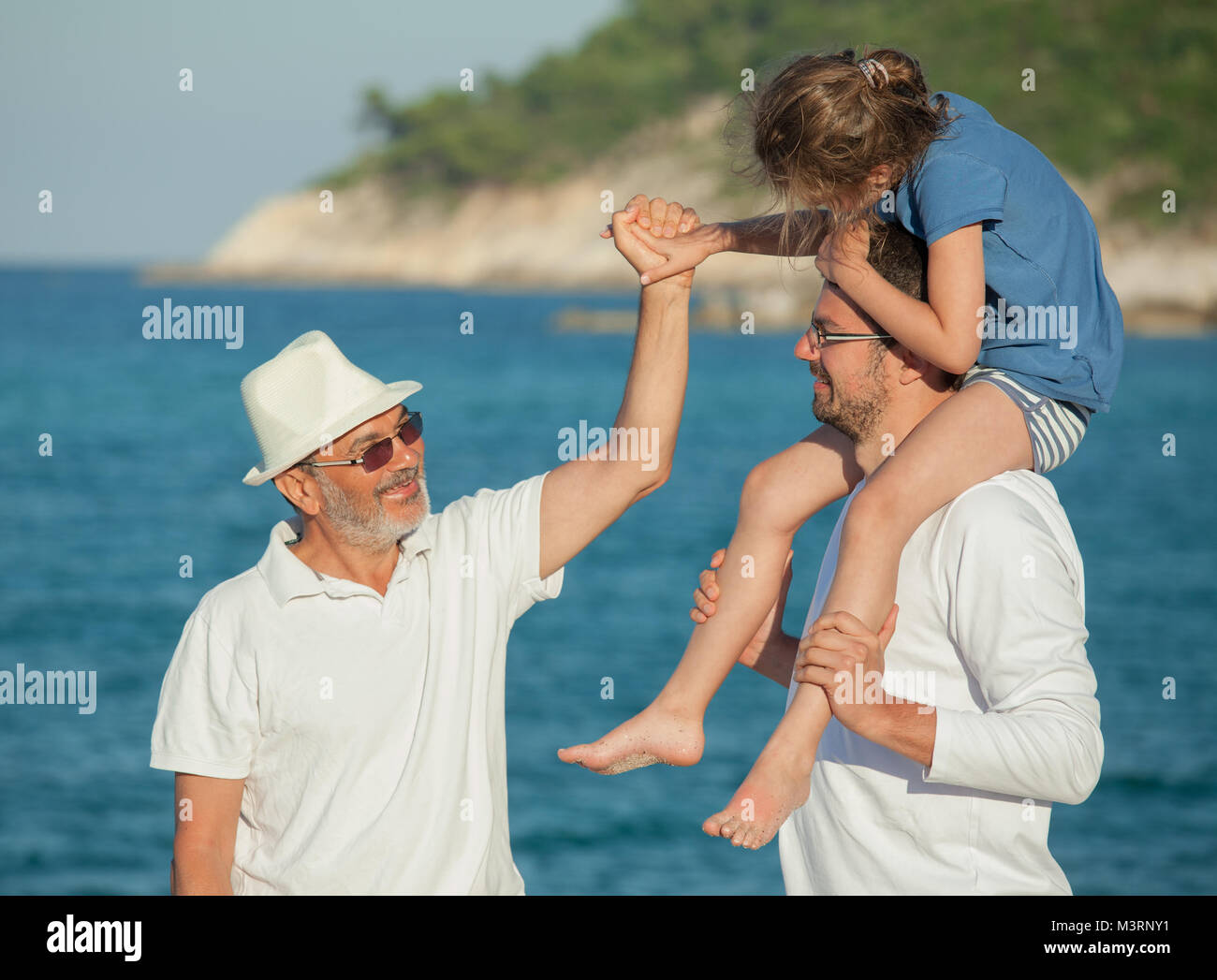 Nonno mare spiaggia mani padre figlia spalle Foto Stock