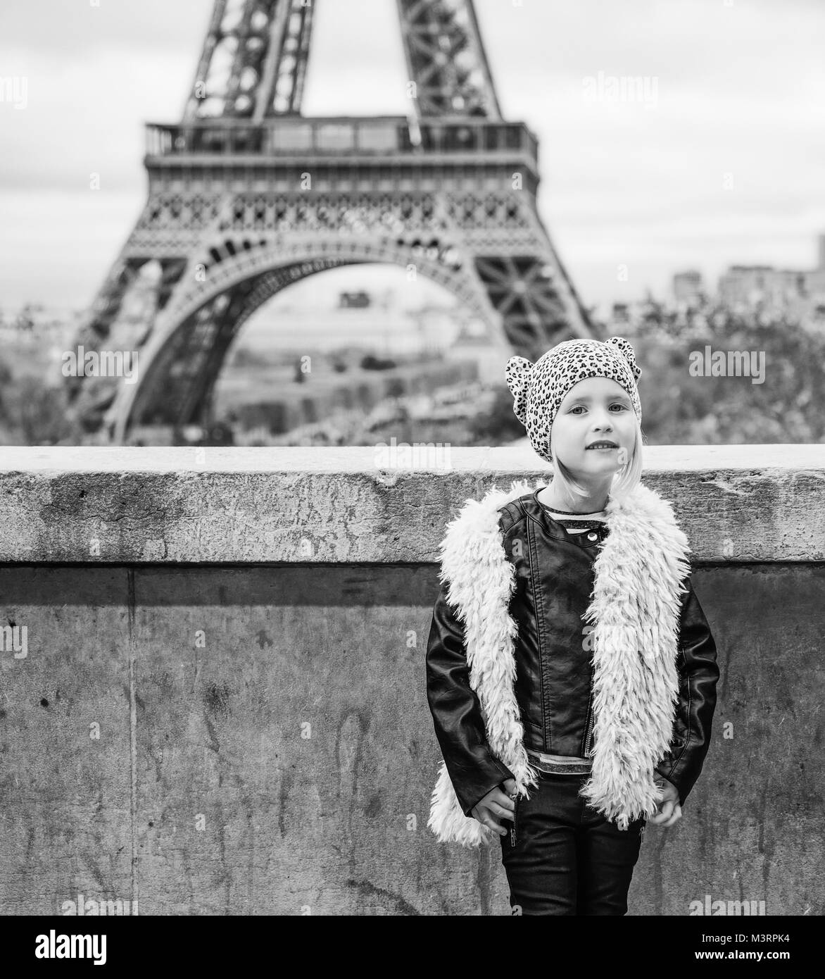 Bold inverno a Parigi. A piena lunghezza ritratto della moderna bambino in piedi contro la Torre Eiffel a Parigi, Francia Foto Stock