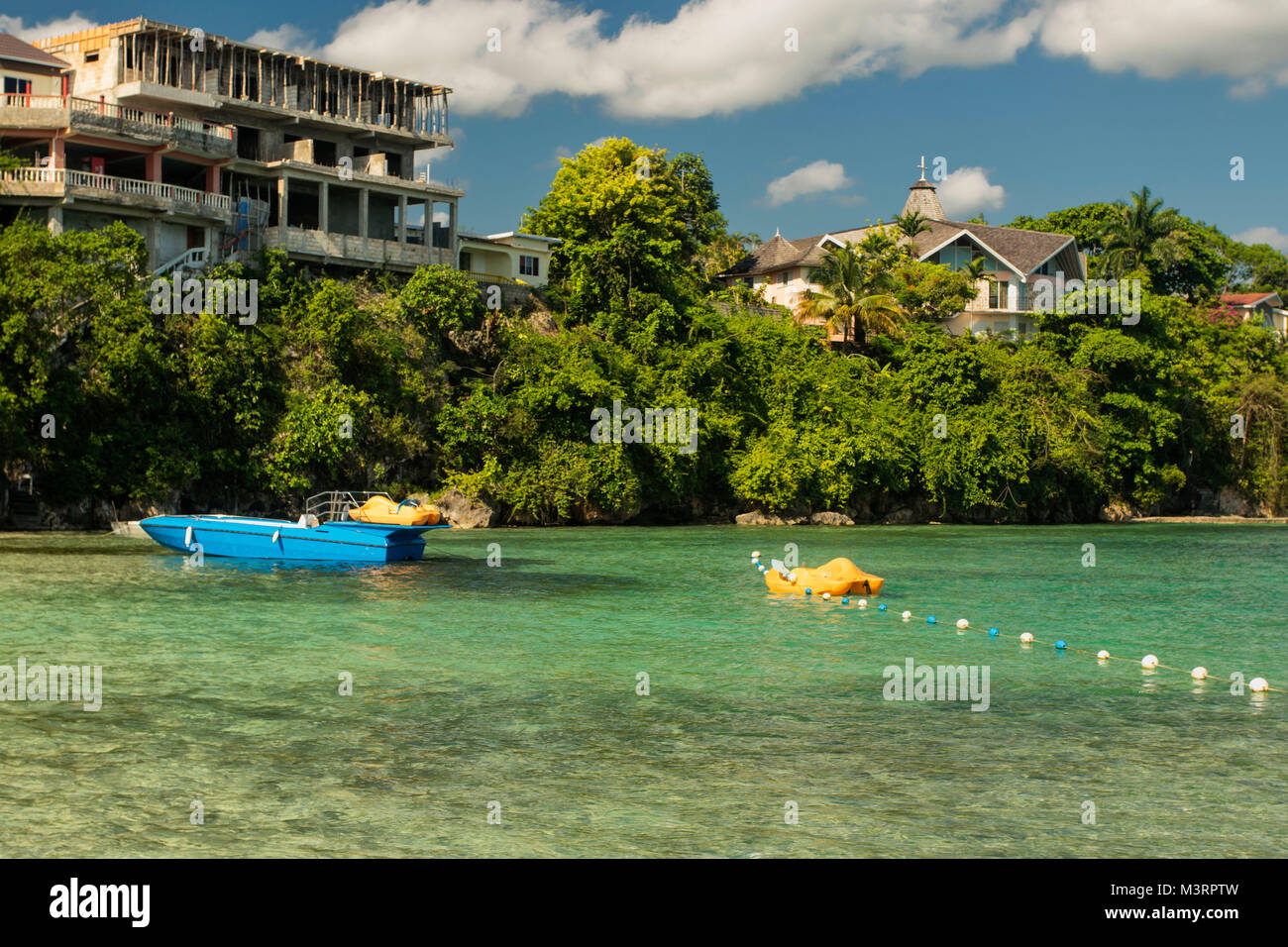 Mogano seascape spiaggia con barca blu, Ocho Rios, Giamaica, West Indies, dei Caraibi Foto Stock