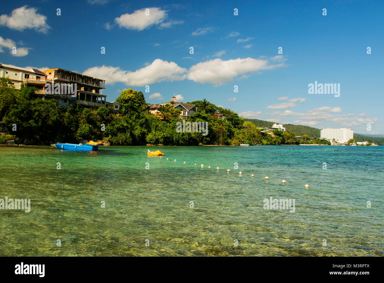 Mogano seascape spiaggia con barca blu, Ocho Rios, Giamaica, West Indies, dei Caraibi Foto Stock