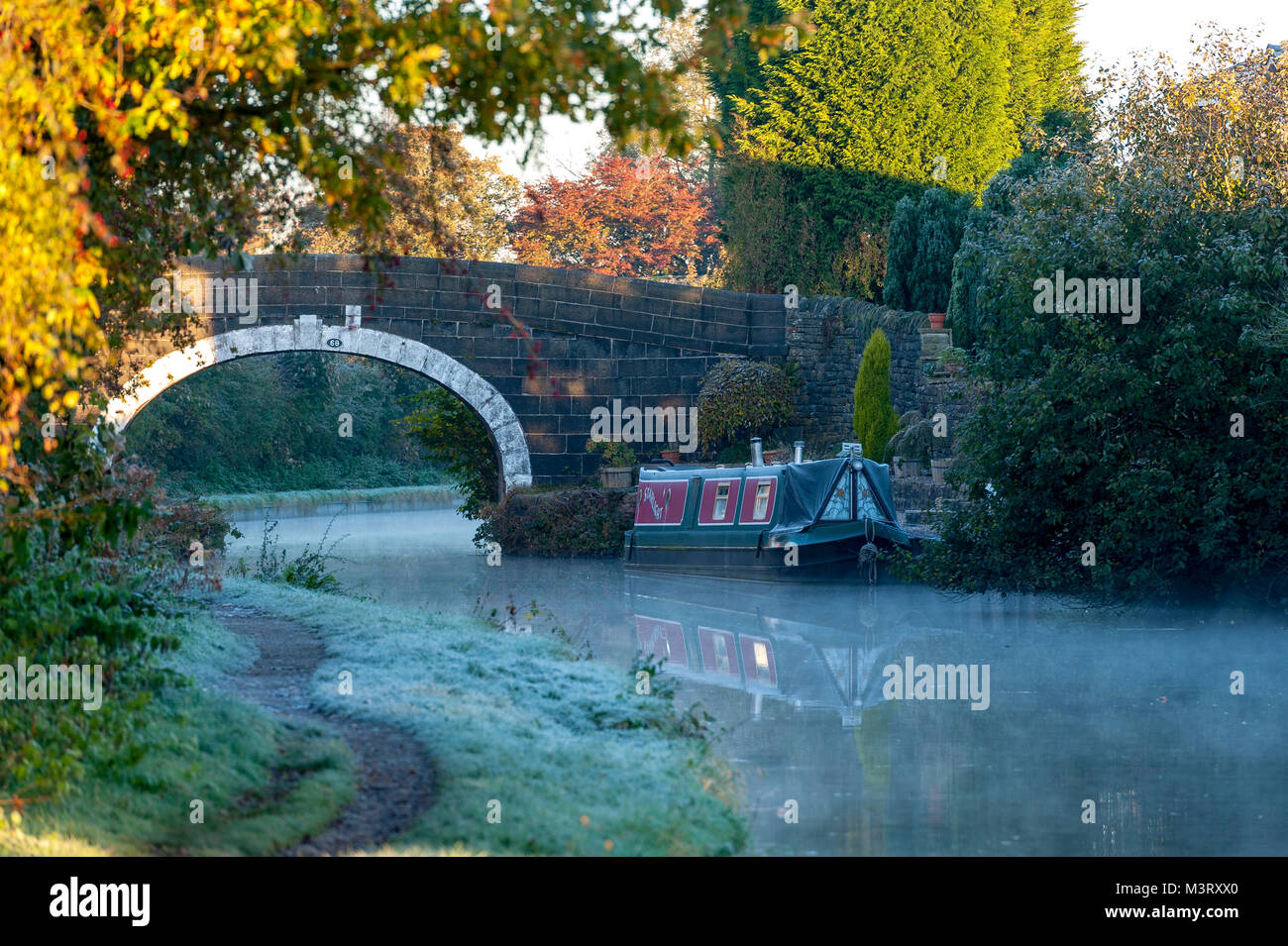 La mattina presto al sole con il gelo e la nebbia in Leeds Liverpool Canal a Adlington LANCASHIRE REGNO UNITO evidenziare un ormeggiati canal boat Foto Stock