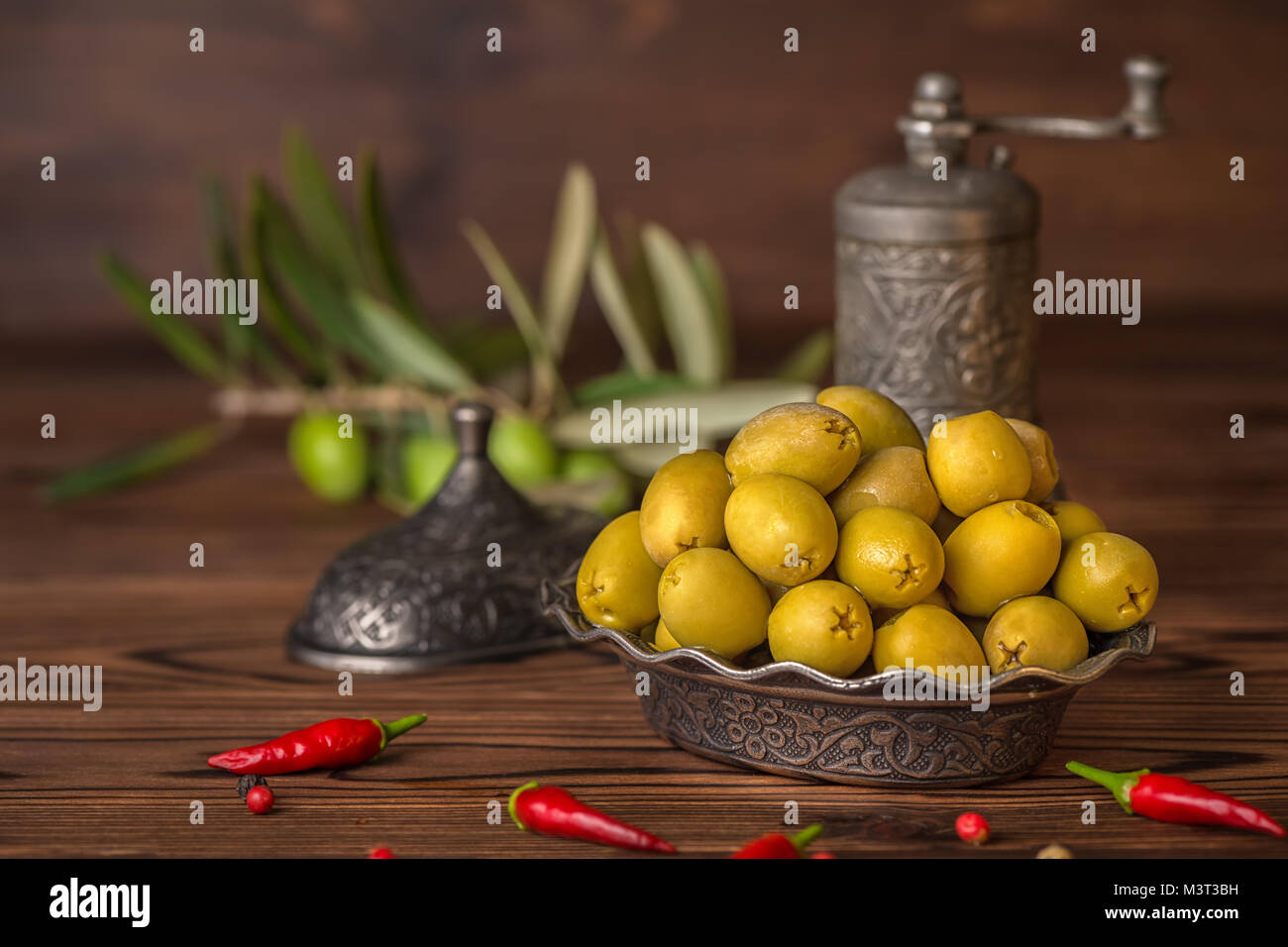Salate olive verdi nella piastra giacciono sullo sfondo di legno decorato Il pepers peperoncino, stile turco Foto Stock
