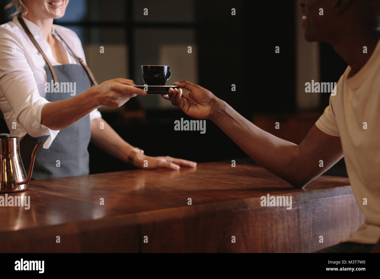 La donna che serve caffè oltre il contatore a un cliente. Ritagliato colpo di coffee shop proprietario consegna una tazza di caffè al suo cliente. Foto Stock
