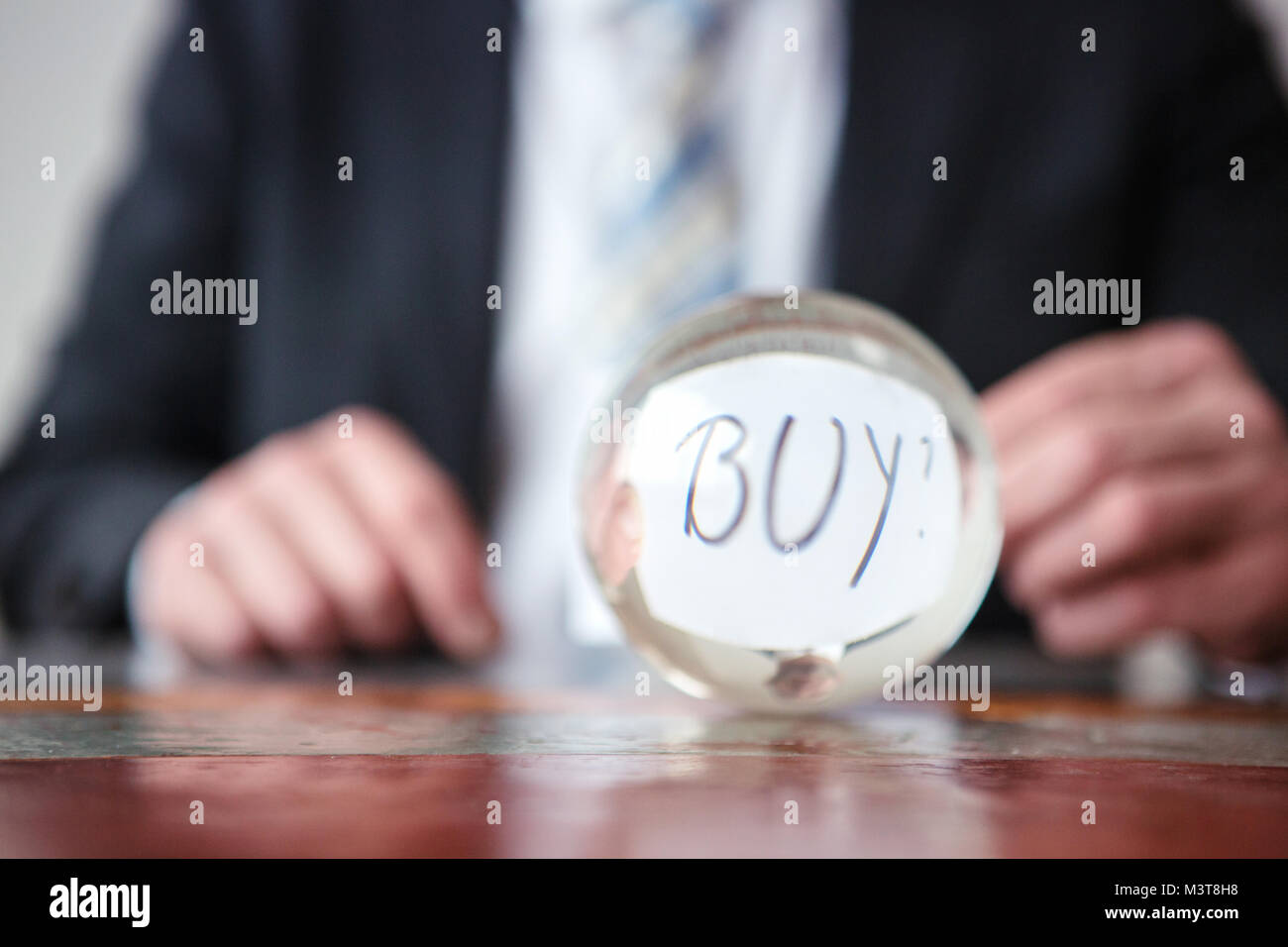 Primo piano di uomo con la carta con la parola Acquista davanti a sfera di vetro Foto Stock