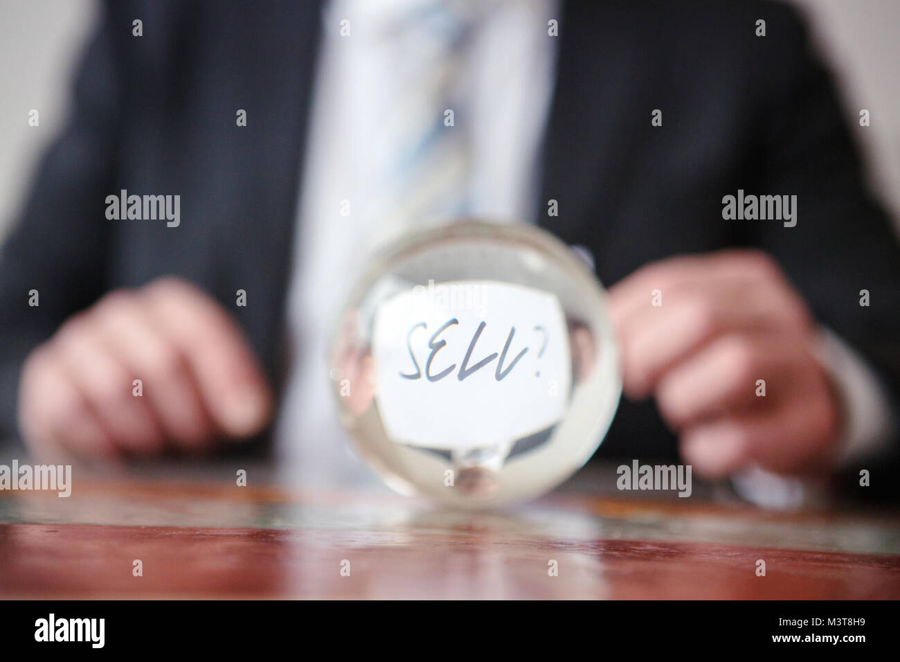 Primo piano di uomo con la carta con la parola vendere davanti a sfera di vetro Foto Stock