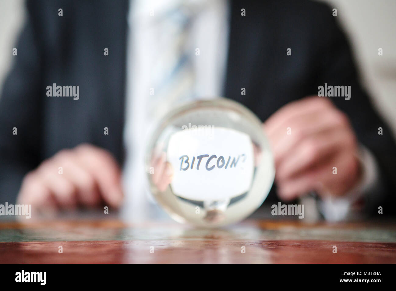 Primo piano dell'uomo tenendo la carta con parola Bitcoin davanti a sfera di vetro Foto Stock