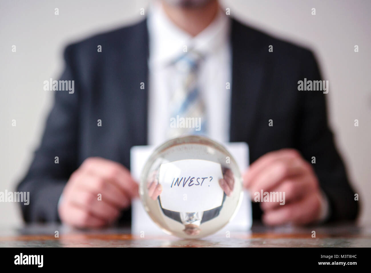 Primo piano di uomo con la carta con la parola investire nella parte anteriore della sfera di vetro Foto Stock