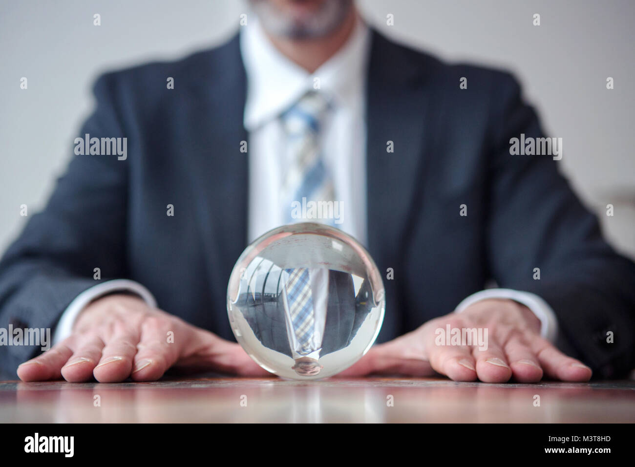 Primo piano di imprenditore guardando a sfera di vetro sul tavolo Foto Stock