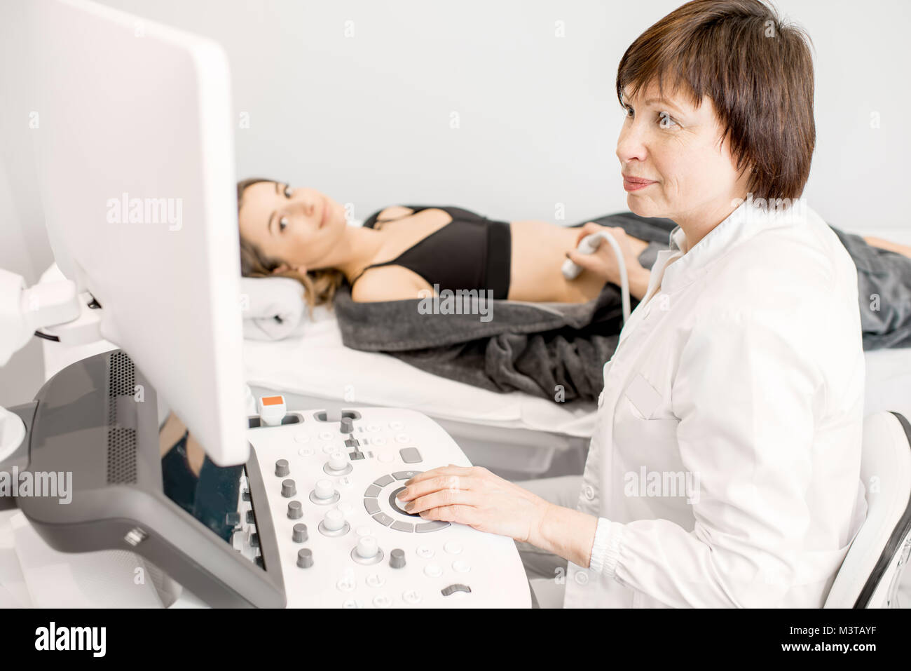 Medico rendendo esame ad ultrasuoni ad una giovane donna Foto Stock