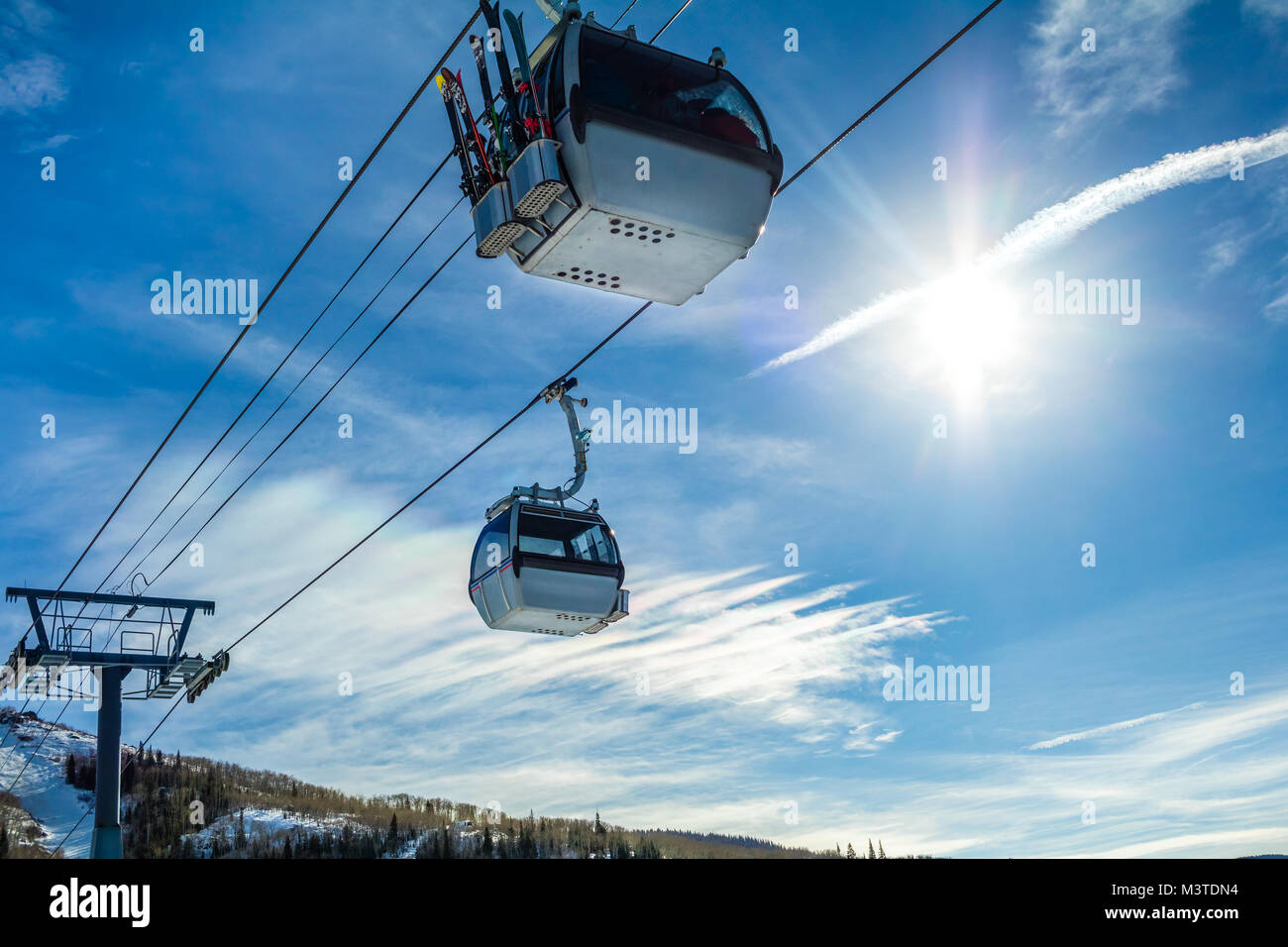 Due ski gondola cabine contro il cielo blu; sole luminoso sulla destra Foto Stock