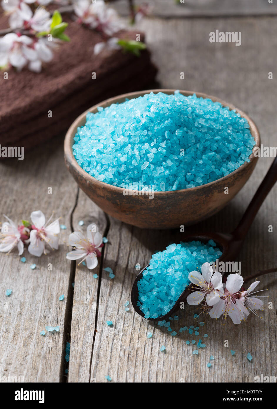 Minerali di sali da bagno, asciugamani e fiori sul vecchio tavolo in legno. DOF poco profondo Foto Stock