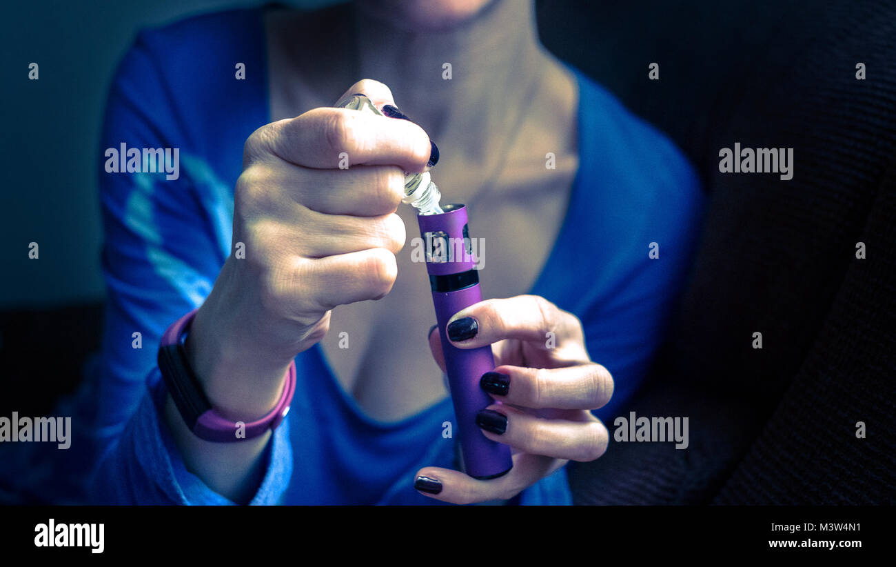 Femmina con e-sigaretta, vaping e ri-riempimento Foto Stock