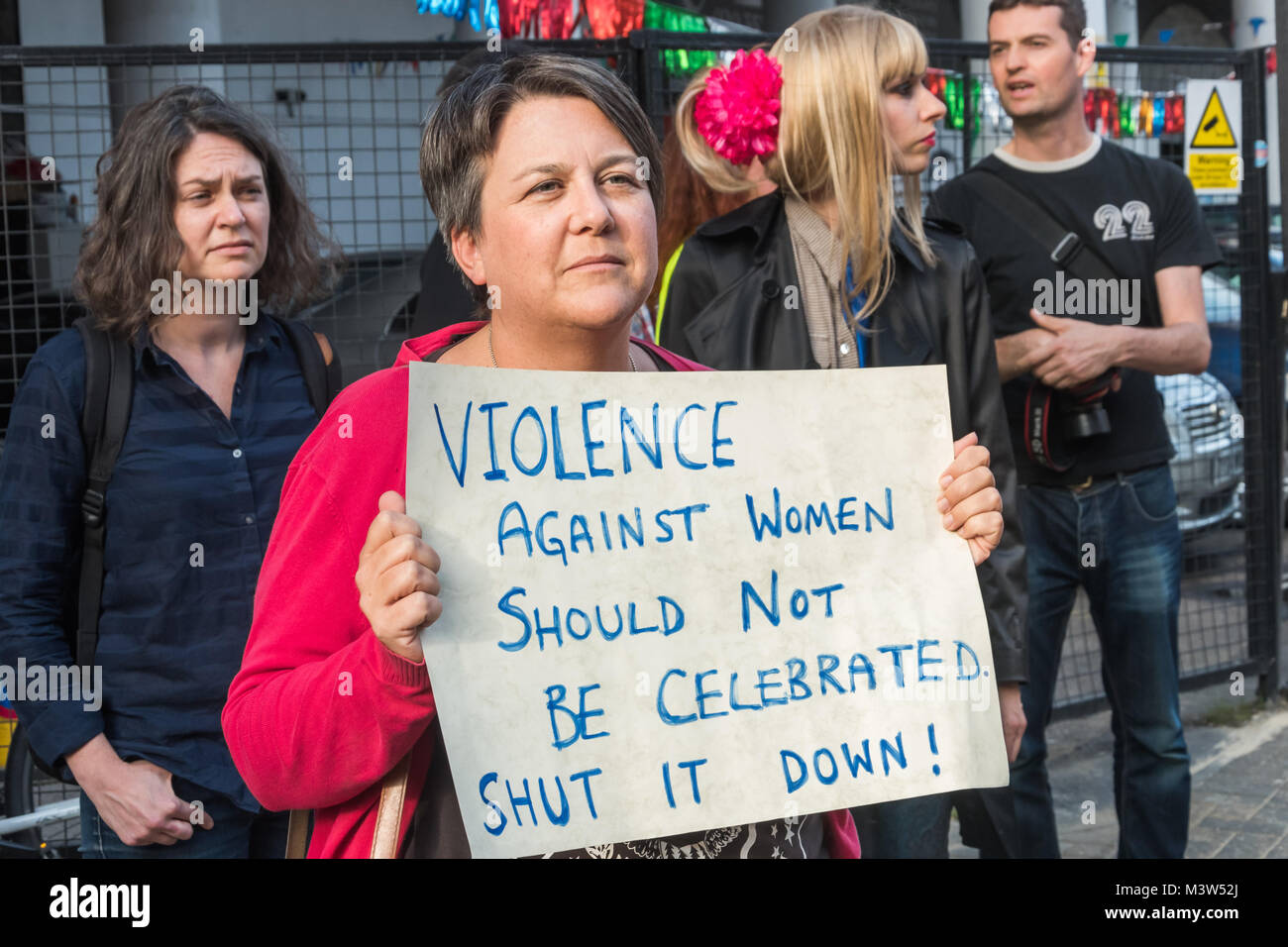 Una donna alla protesta contro il Jack lo Squartatore museo conserva un poster "Violenza contro le donne non dovrebbero essere celebrato. Spegnere!' Foto Stock