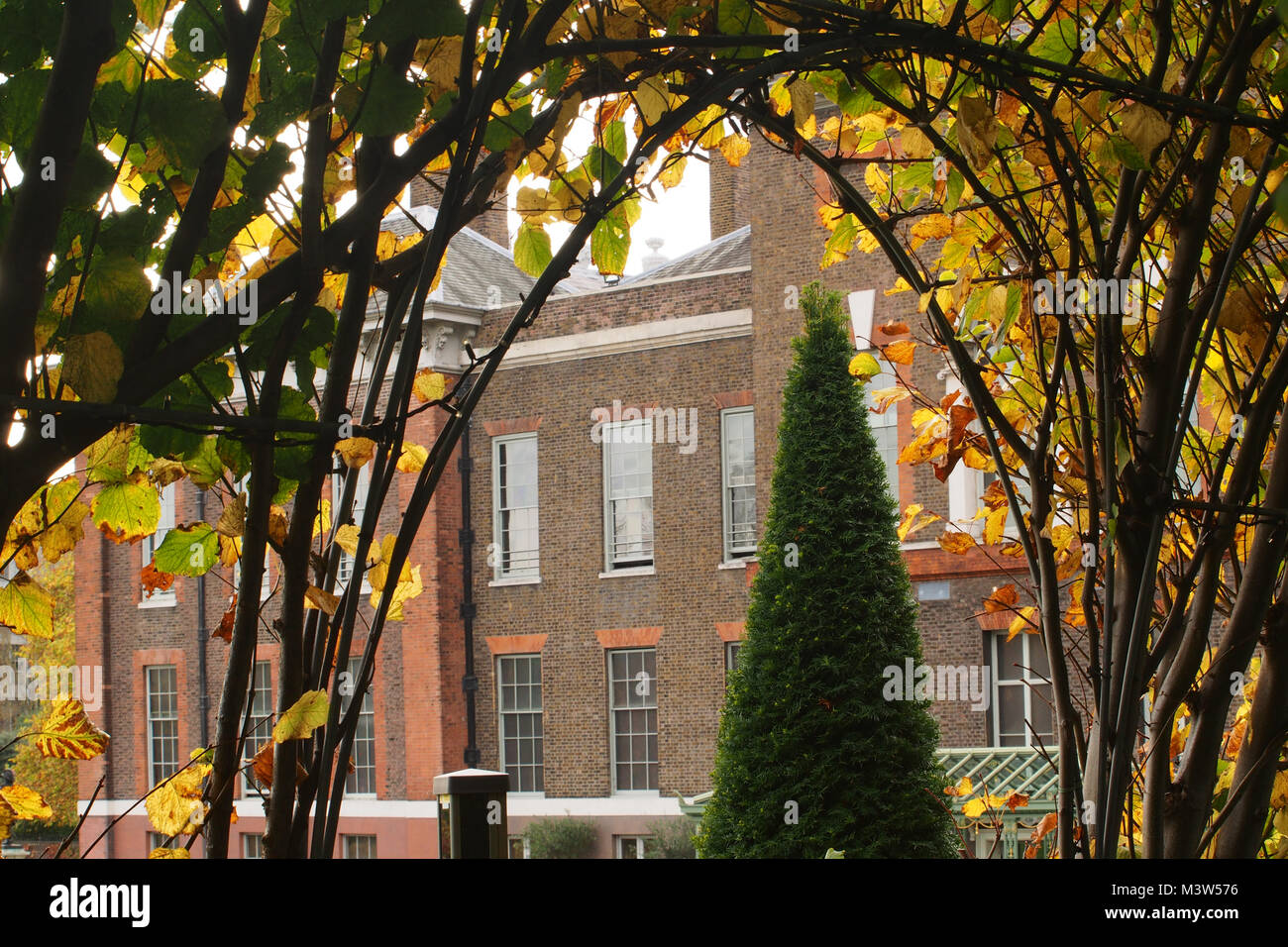 Una vista di una sezione di Kensington Palace da sunken giardino incorniciato da un addestrato tree archway Foto Stock