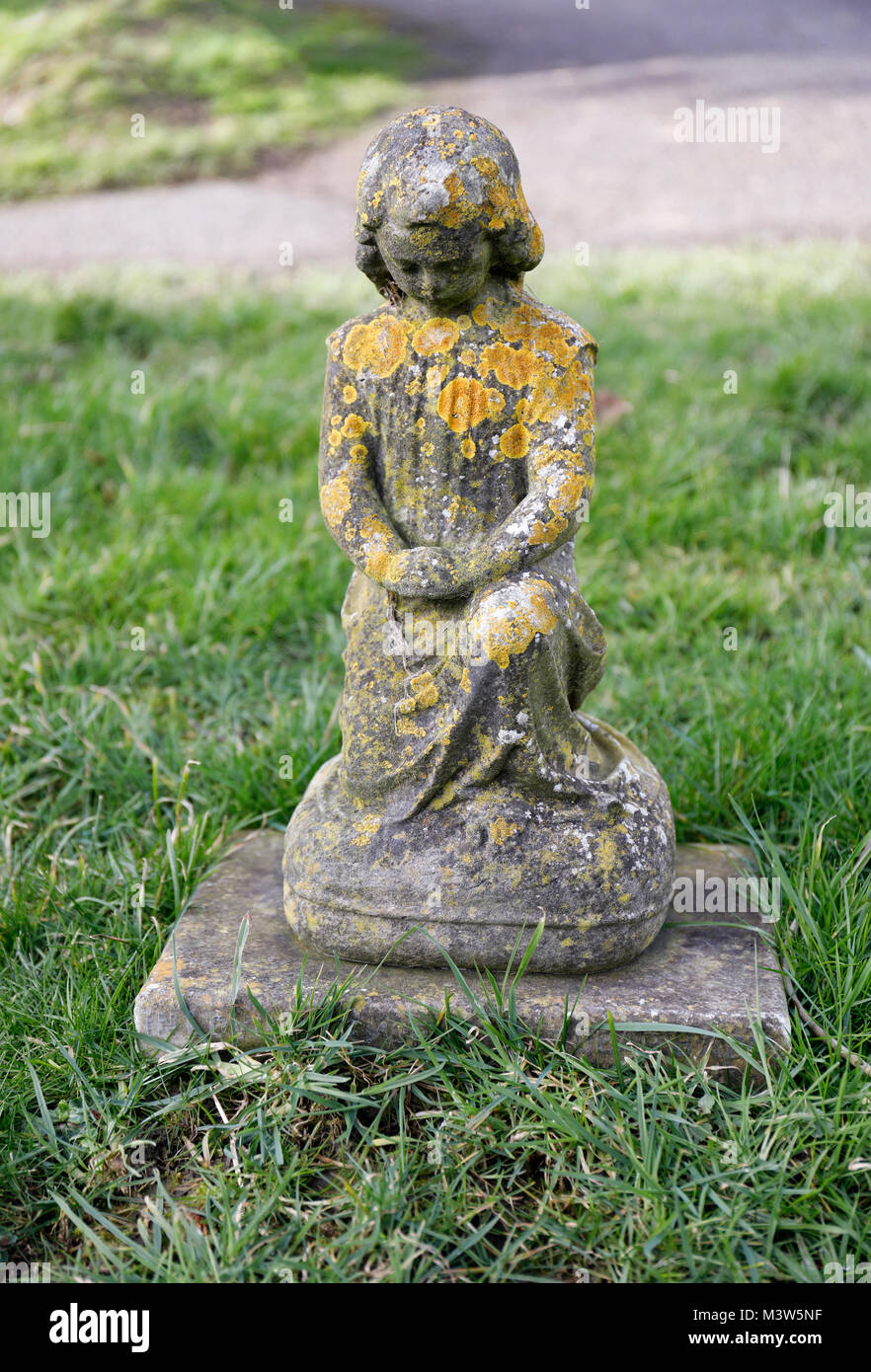 Statua in pietra di un bambino inginocchiato nella preghiera nel cimitero di Christ Church, Frome, Somerset, Inghilterra Foto Stock