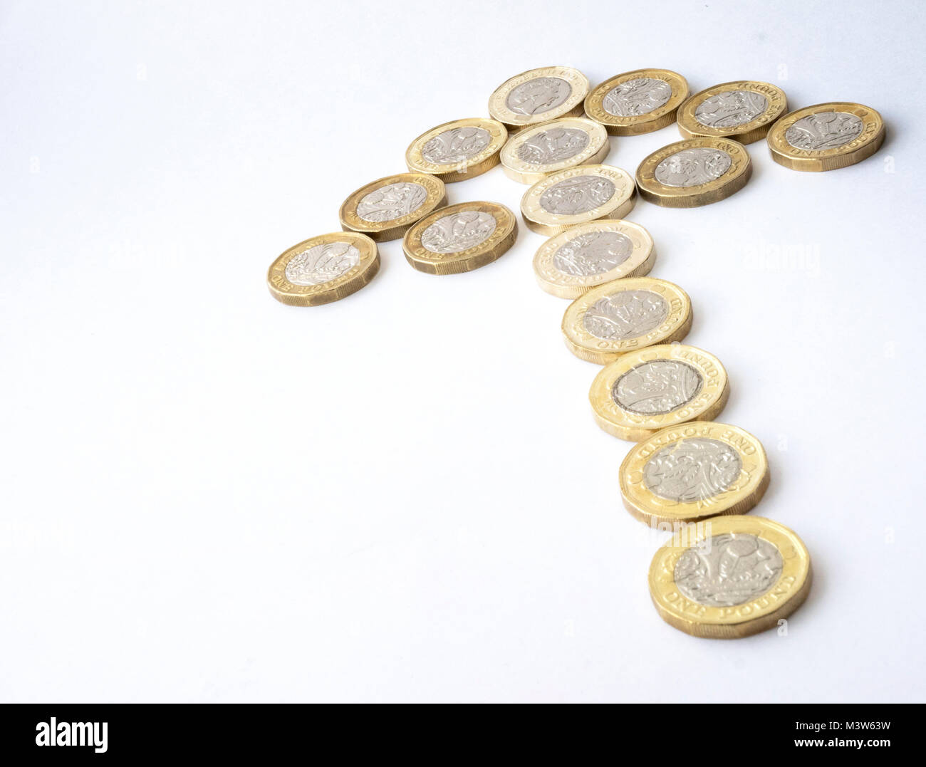 Diversi nuovi dodici lati sterlina britannica monete disposte sotto forma di una freccia che denota una tendenza al rialzo Foto Stock