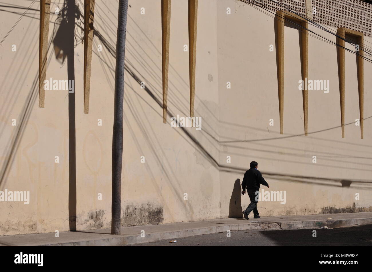 Un pedone a piedi nella parte anteriore di una parete gialla sulla strada in Sucre, Bolivia Foto Stock