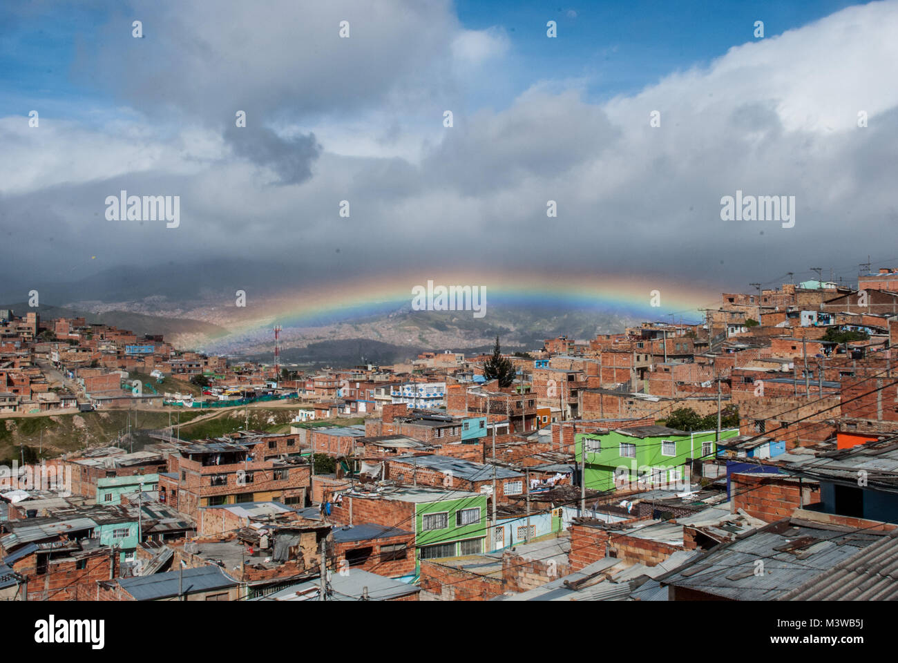 Un arcobaleno appeso nel cielo blu su una bidonville nel sud di Bogotà, Colombia Foto Stock