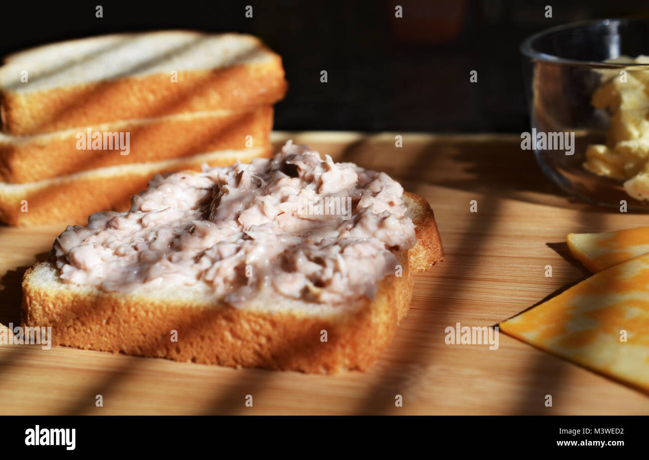 Tonno Insalata di pesce spalmato sul pane bianco faccia aperta stile, con burro nella ciotola di vetro e bianco e giallo le fette di formaggio Foto Stock