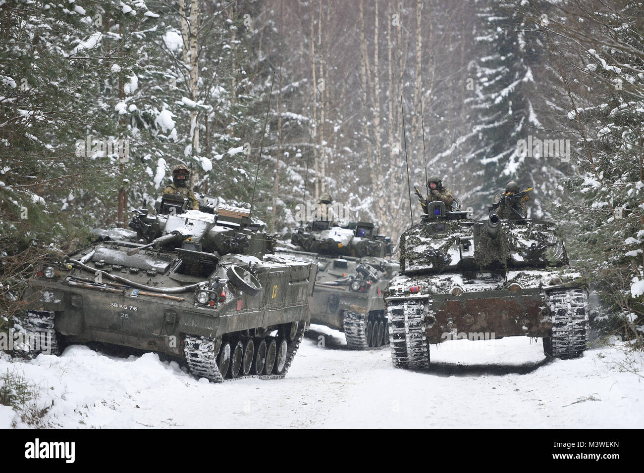 Un carro armato Challenger 2 passa un paio di veicoli blindati con cingoli Warrior in un'area di addestramento vicino a Tapa in Estonia, mentre il primo battaglione il Royal Welsh partecipa all'Esercitazione del campo invernale, dove le truppe britanniche sono pronte a difendersi da una Russia potenzialmente aggressiva accanto agli alleati della NATO. Foto Stock