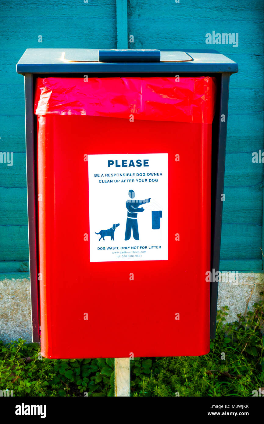 Rosso brillante bin situato fuori per il cane dei rifiuti, con una lettura di etichetta: "Si prega di essere responsabile di un proprietario del cane. Pulizia dopo il vostro cane." L'Inghilterra, Regno Unito. Foto Stock