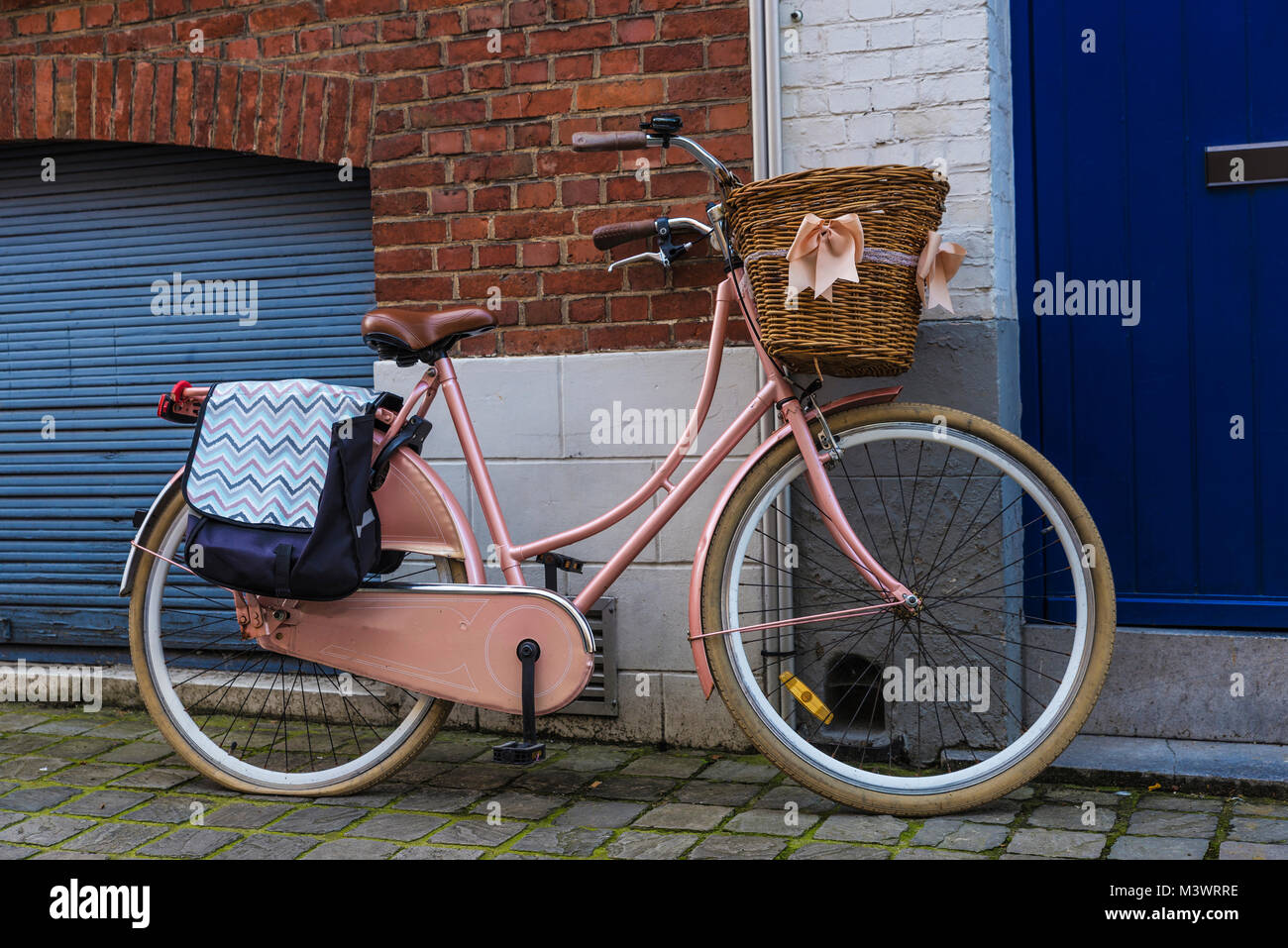 Vecchia bicicletta vintage con un cesto di vimini con nastri parcheggiato su una strada della città medievale di Bruges, Belgio Foto Stock