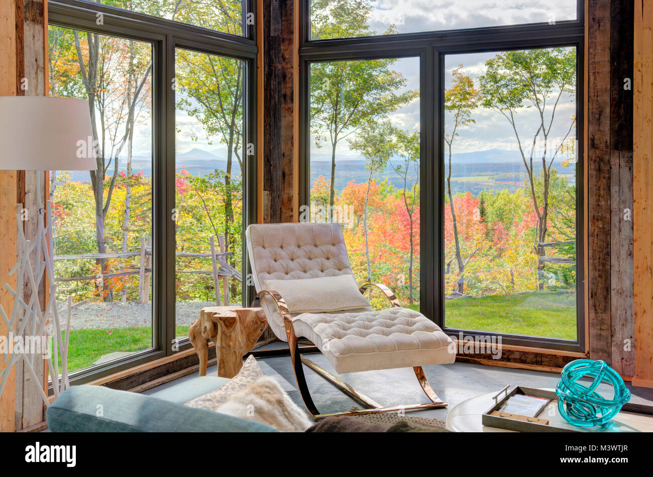 Rilassante soggiorno in scena secondario di lusso residence chalet con una vista fuori le grandi finestre di montagne e la caduta delle foglie. Foto Stock