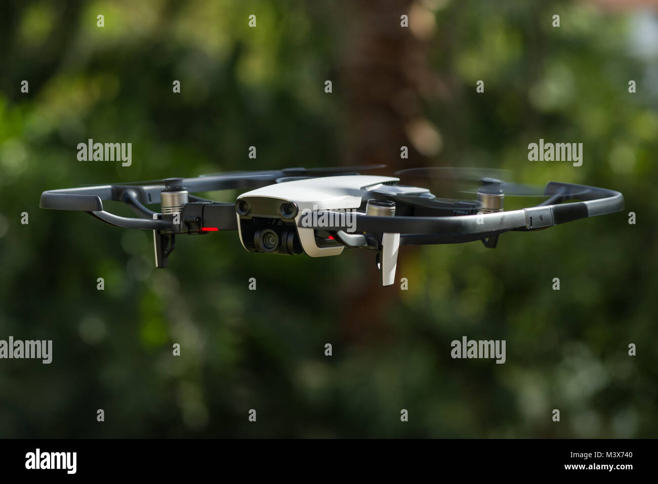 Un DJI Mavic aria drone in volo contro un verde scuro dello sfondo ad albero Foto Stock