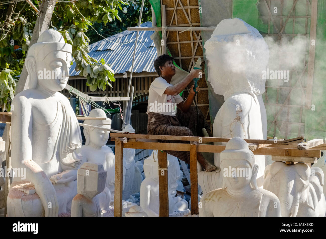 Un lavoratore è la macinazione di una statua del Buddha da un solido blocco di marmo bianco Foto Stock