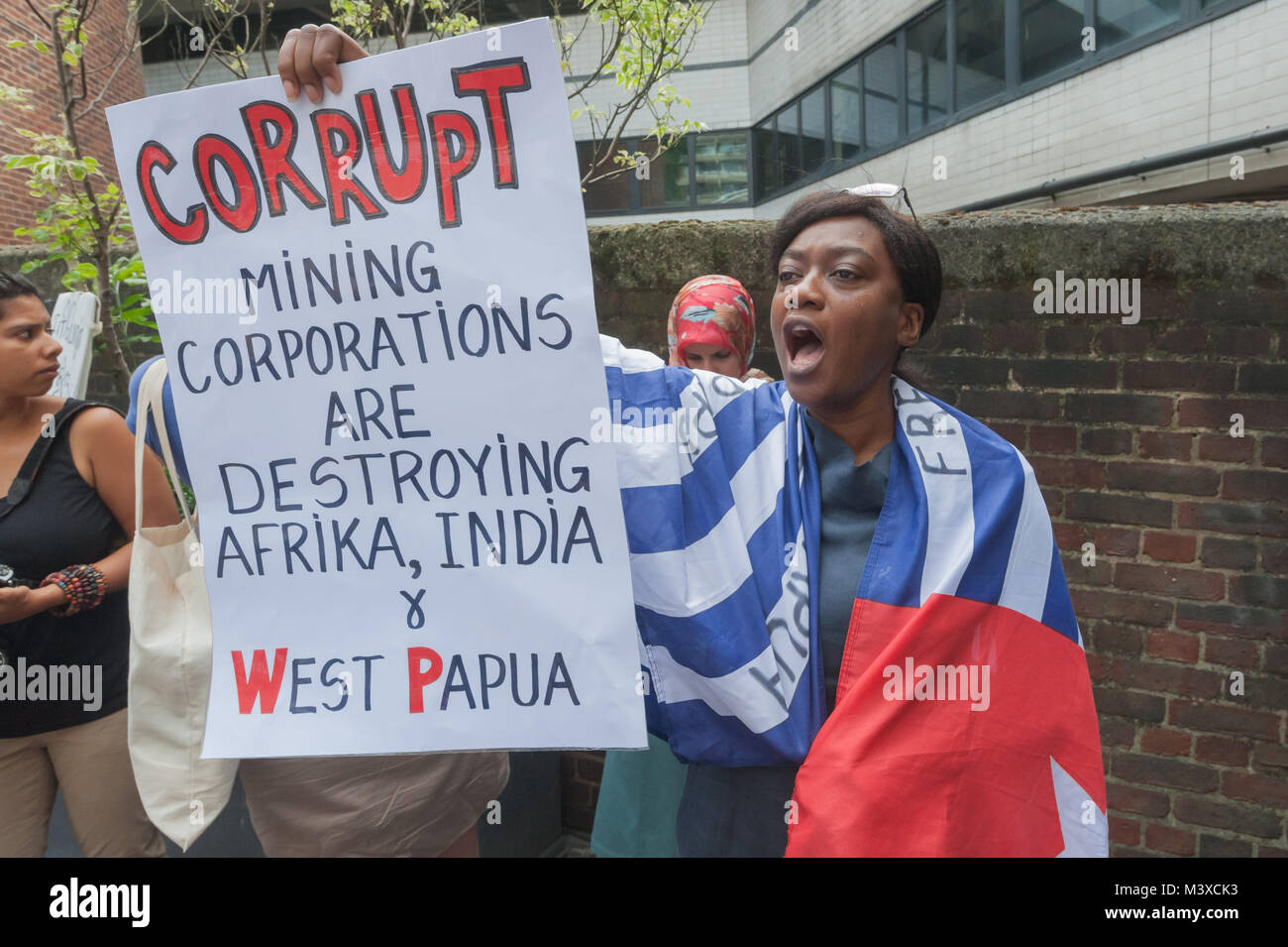 Una donna drappeggiati in Papua Occidentale bandiera tiene un poster su corrotto le società minerarie fuori dall'assemblea generale degli azionisti del Vedanta, soprannominato 'il mondo più odiato mining company" per la sua envrionmental e le violazioni dei diritti umani in tutto il mondo. Foto Stock
